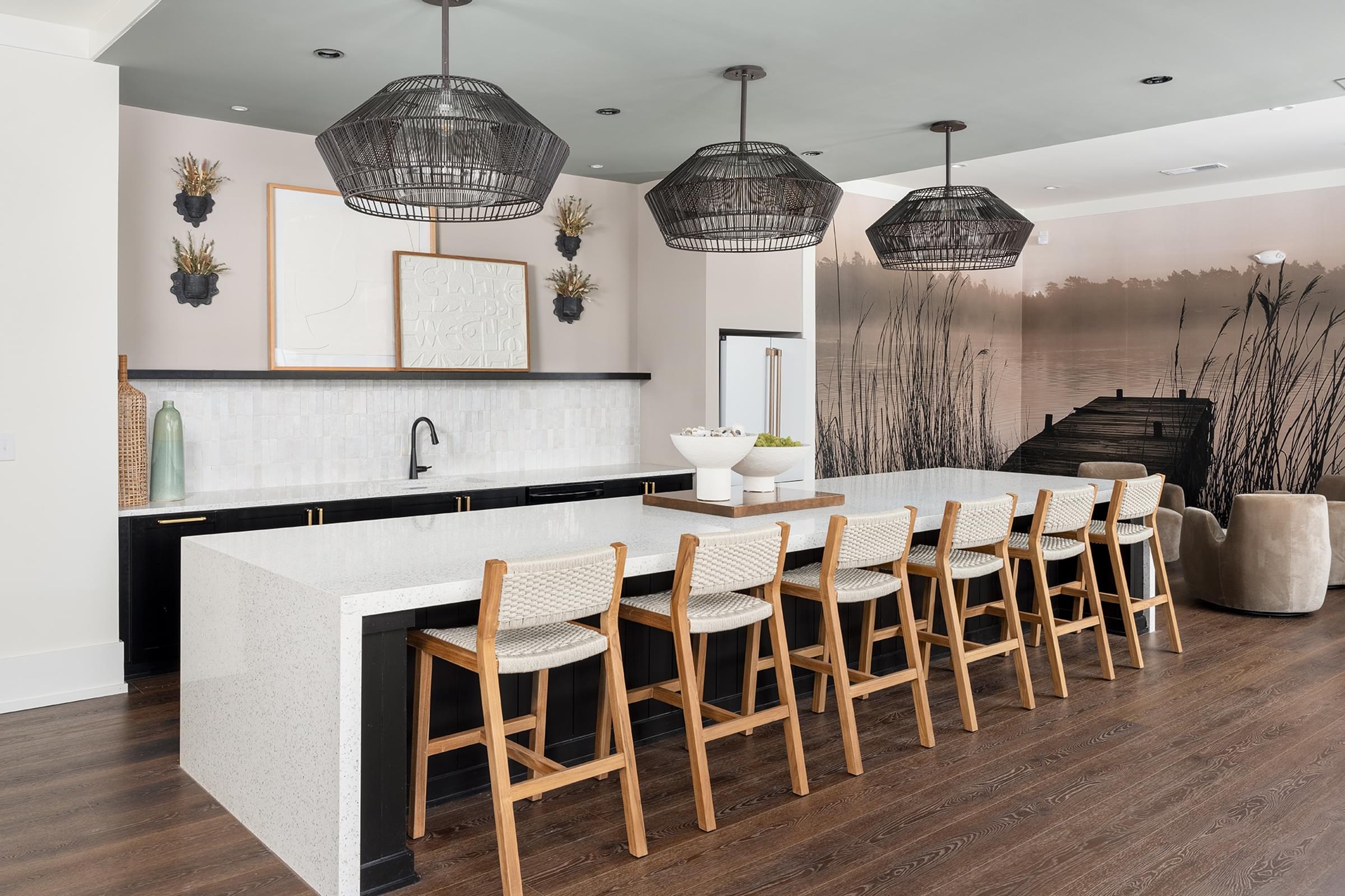 A modern kitchen with a white island and wooden chairs.