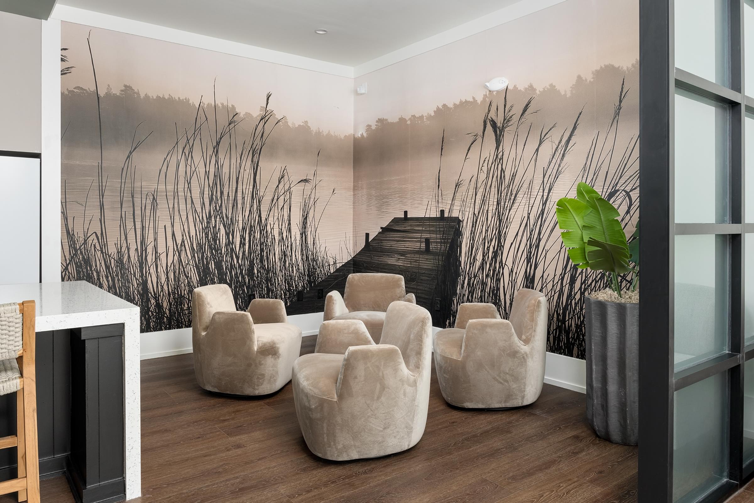 A room with a wall mural of a lake and reeds, with a white table and chairs.