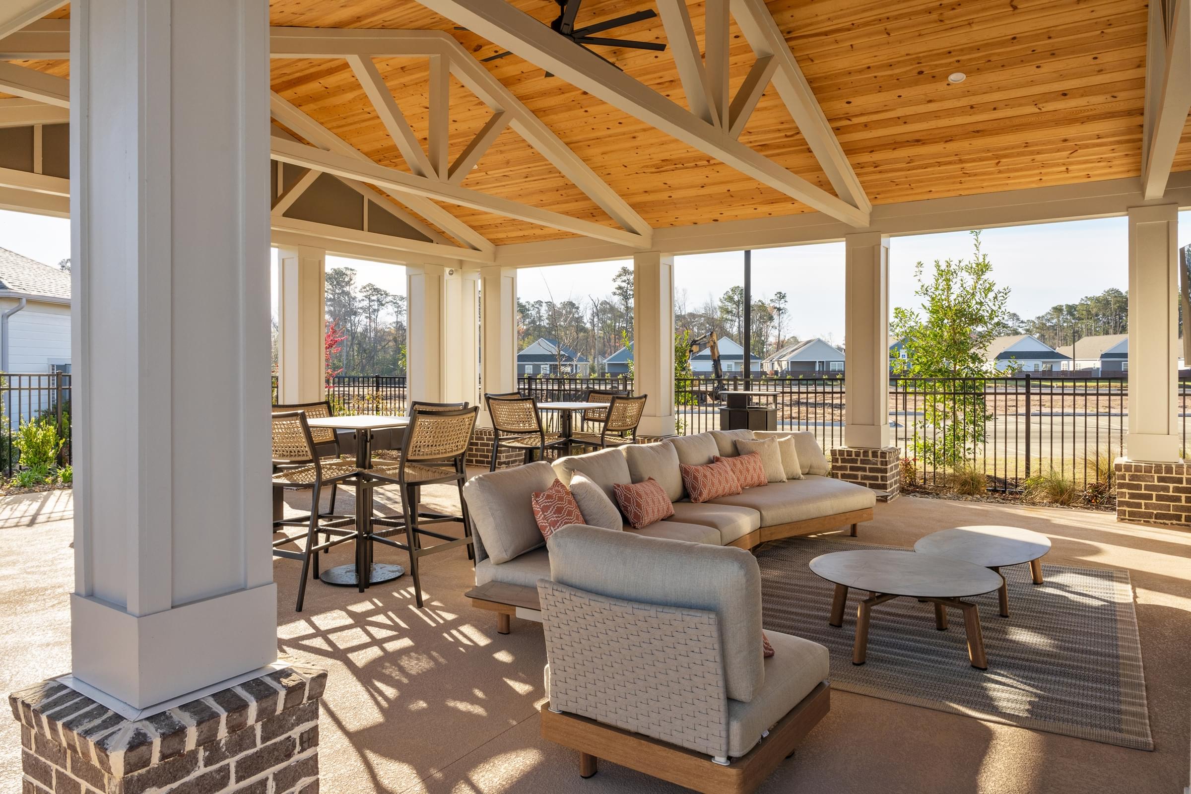 A sunny day at a covered outdoor patio with a couch, chairs, and a coffee table.