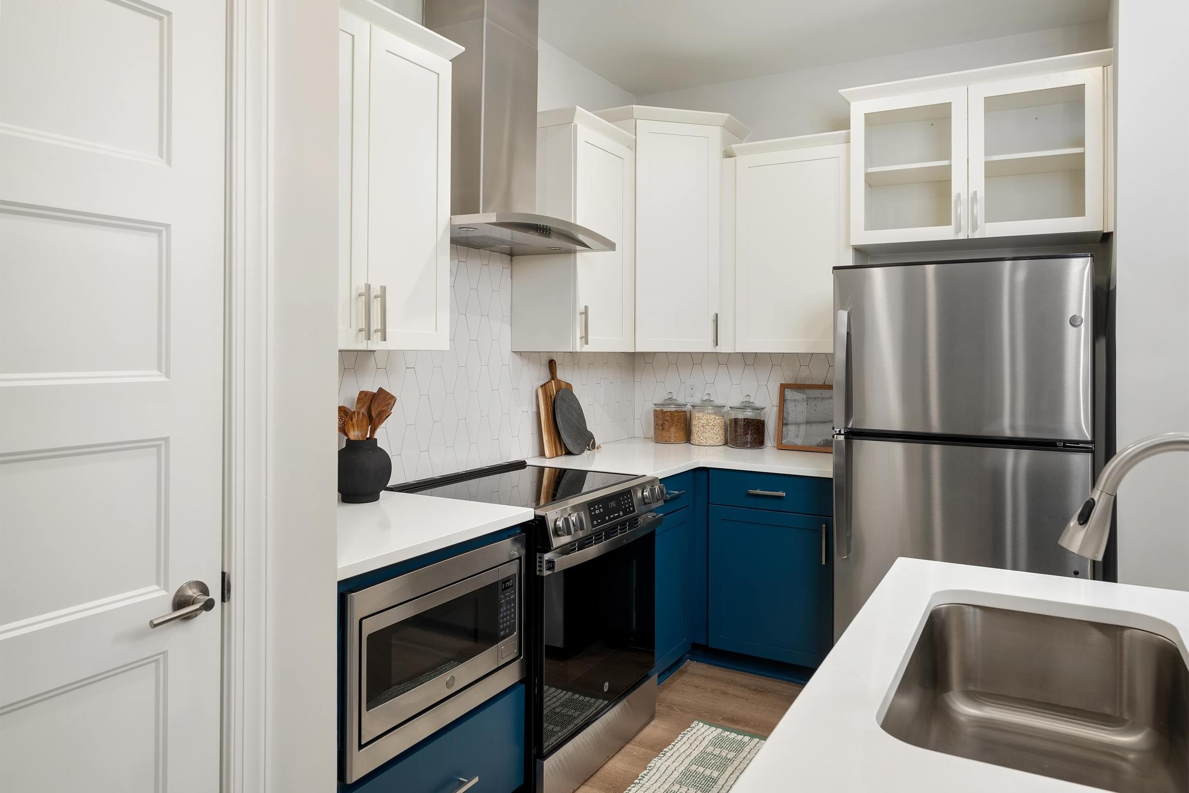 A kitchen with blue cabinets and a stainless steel refrigerator.