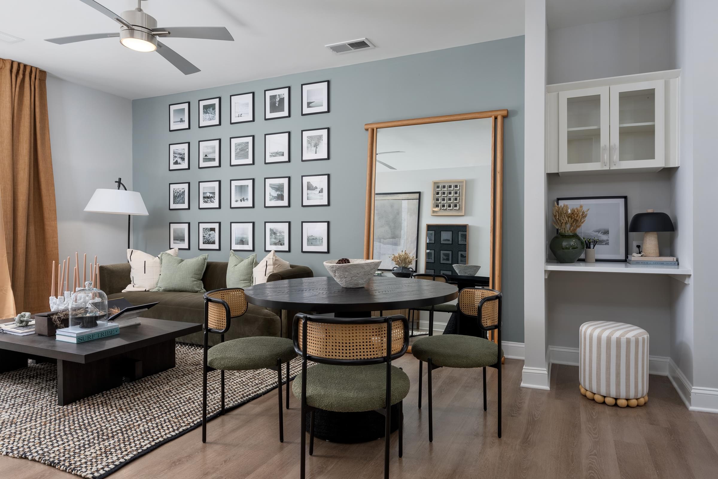 A living room with a table, chairs, and a wall of pictures.