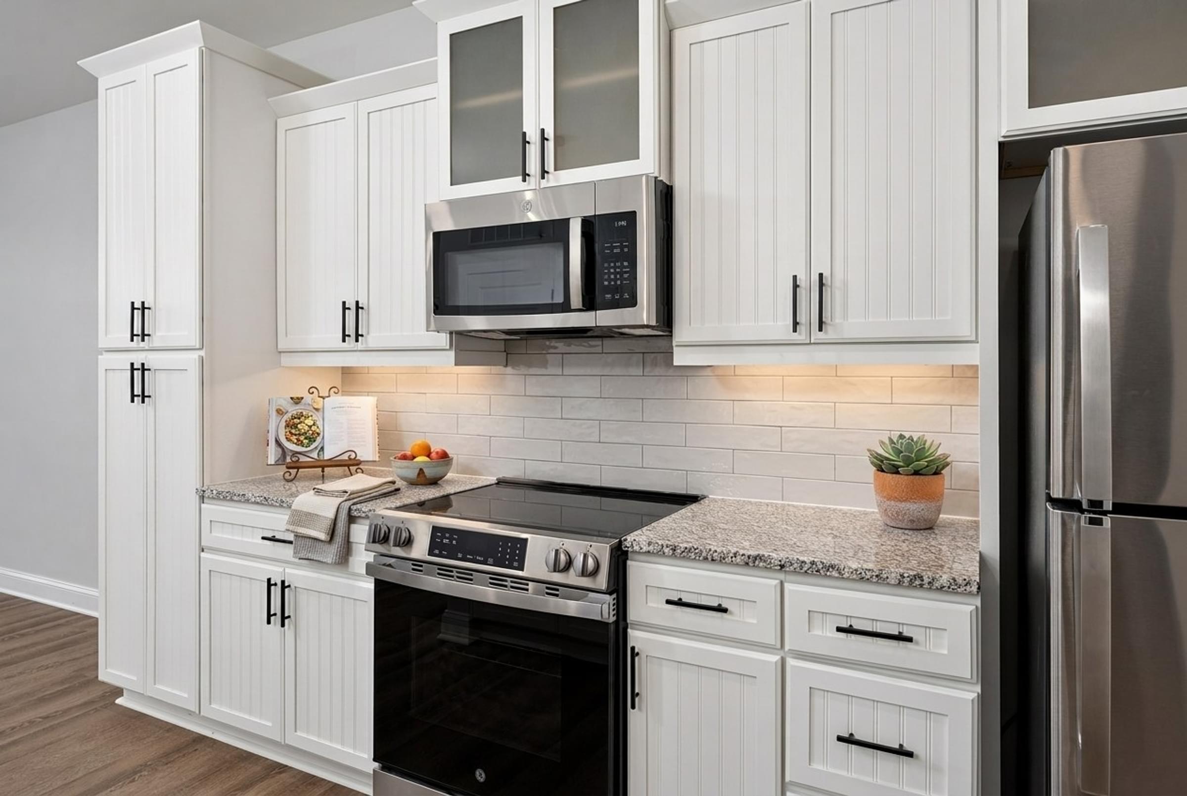 A modern kitchen with white cabinets and stainless steel appliances.