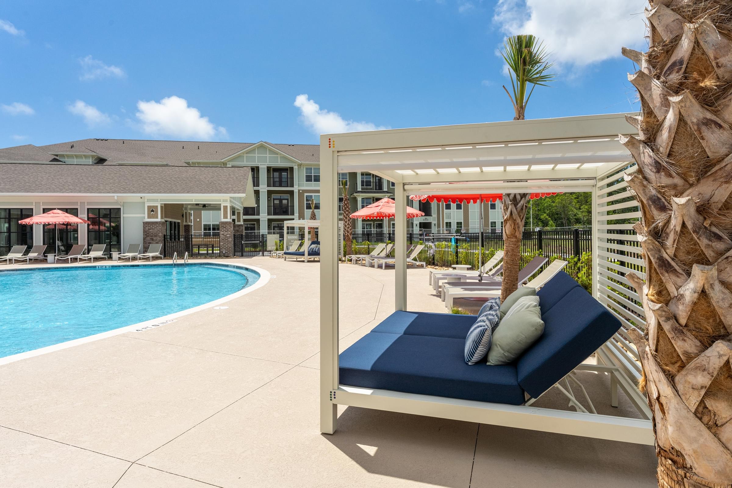 A poolside lounge chair with a cushion and a pillow is positioned in front of a pineapple.