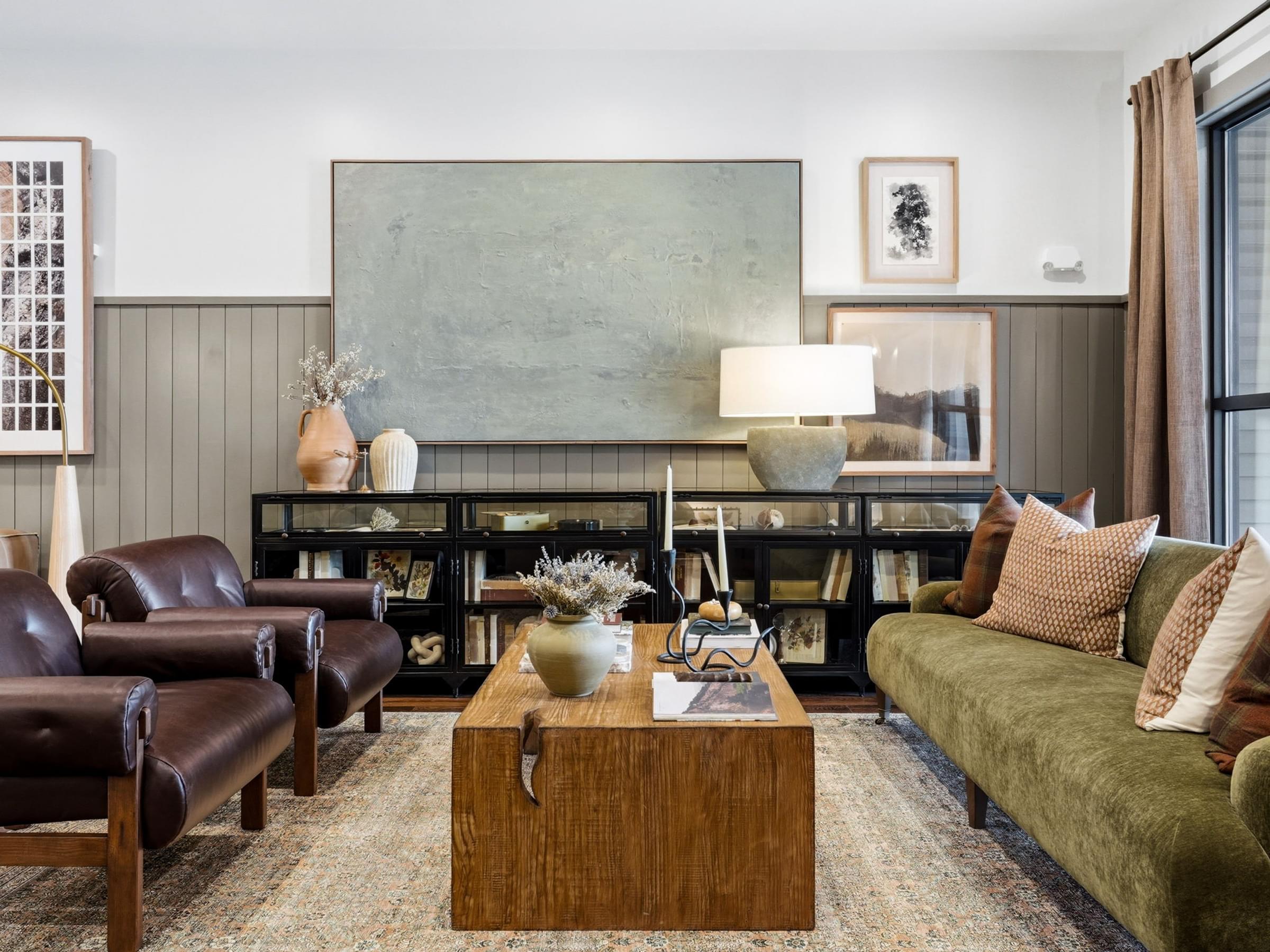A living room with a green couch and brown leather chairs.