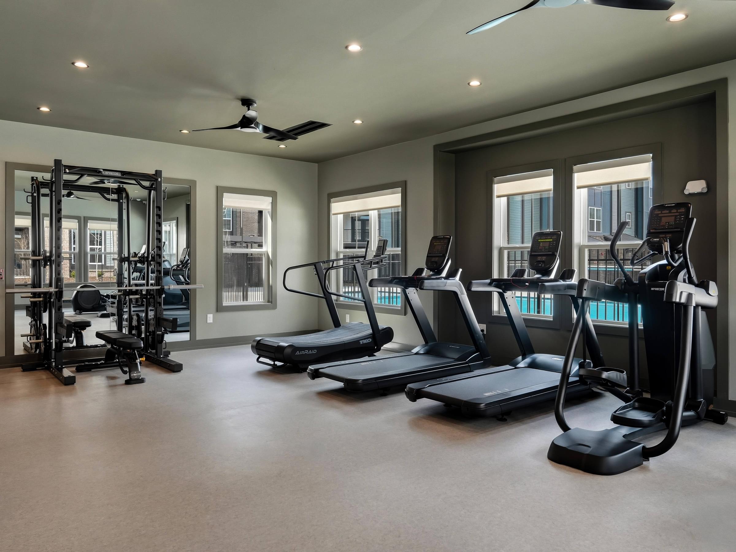 A spacious gym with treadmills, elliptical machines, and a weight training area.