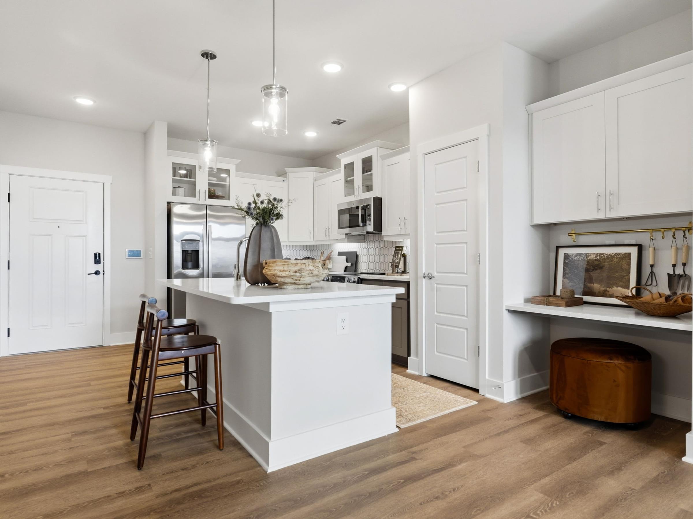 A kitchen with white cabinets and a wooden floor.