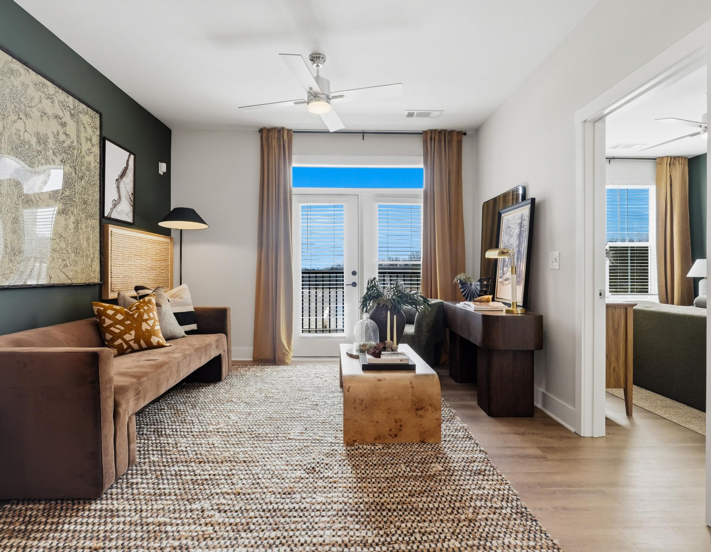 A living room with a brown couch, a coffee table, and a ceiling fan.