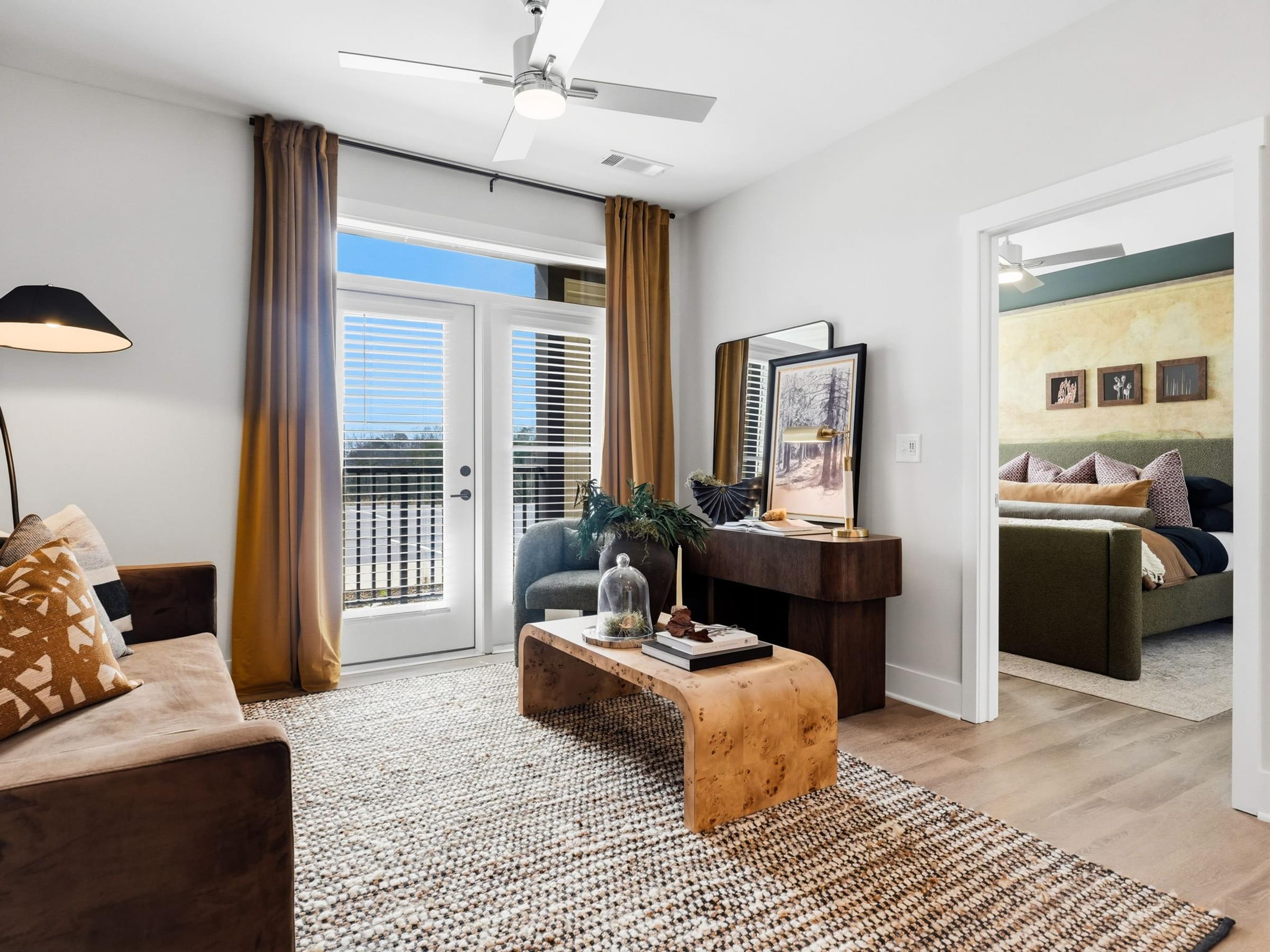 A living room with a brown couch, a coffee table, and a ceiling fan.