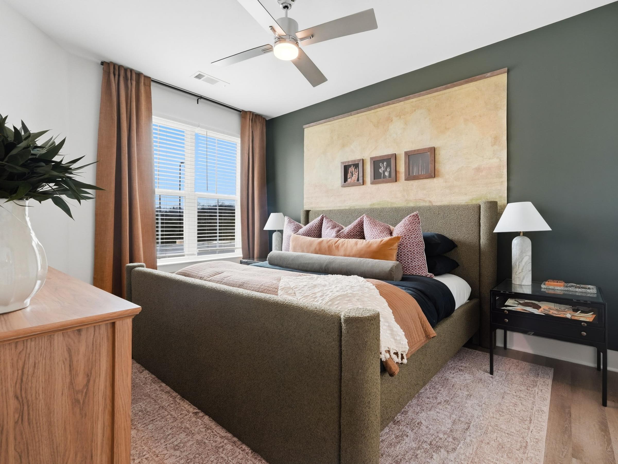 A bedroom with a bed, nightstand, and a ceiling fan.
