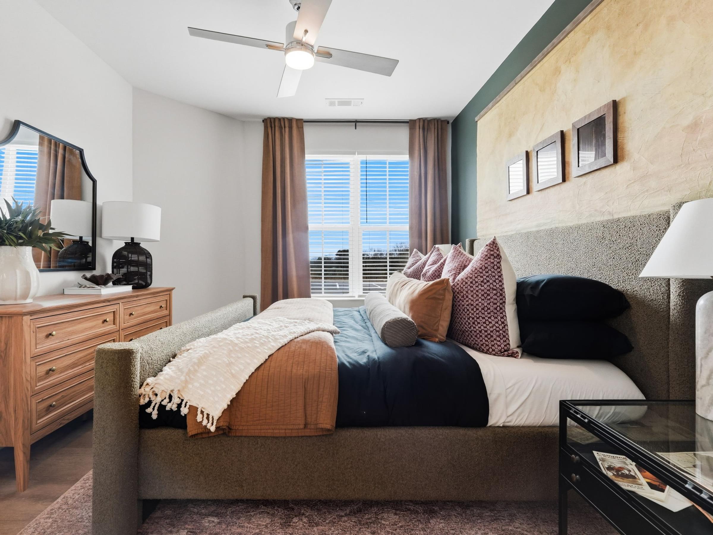 A bedroom with a bed, nightstand, and window with curtains.