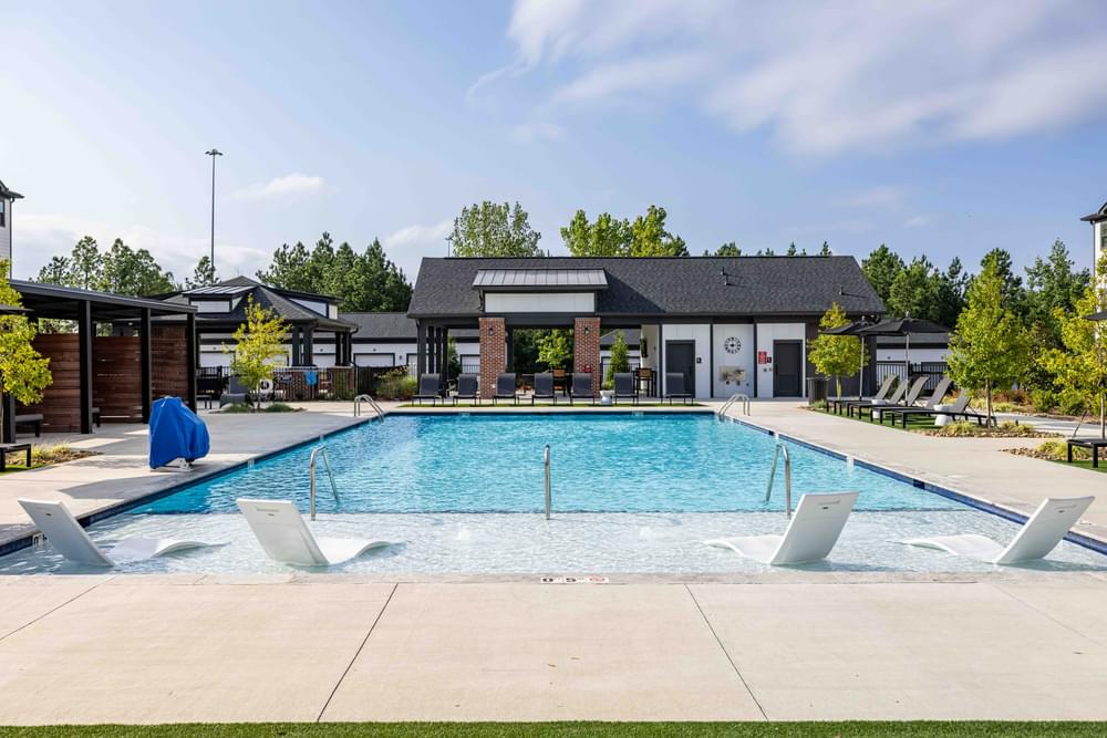 A large outdoor swimming pool with a diving board and lounge chairs.