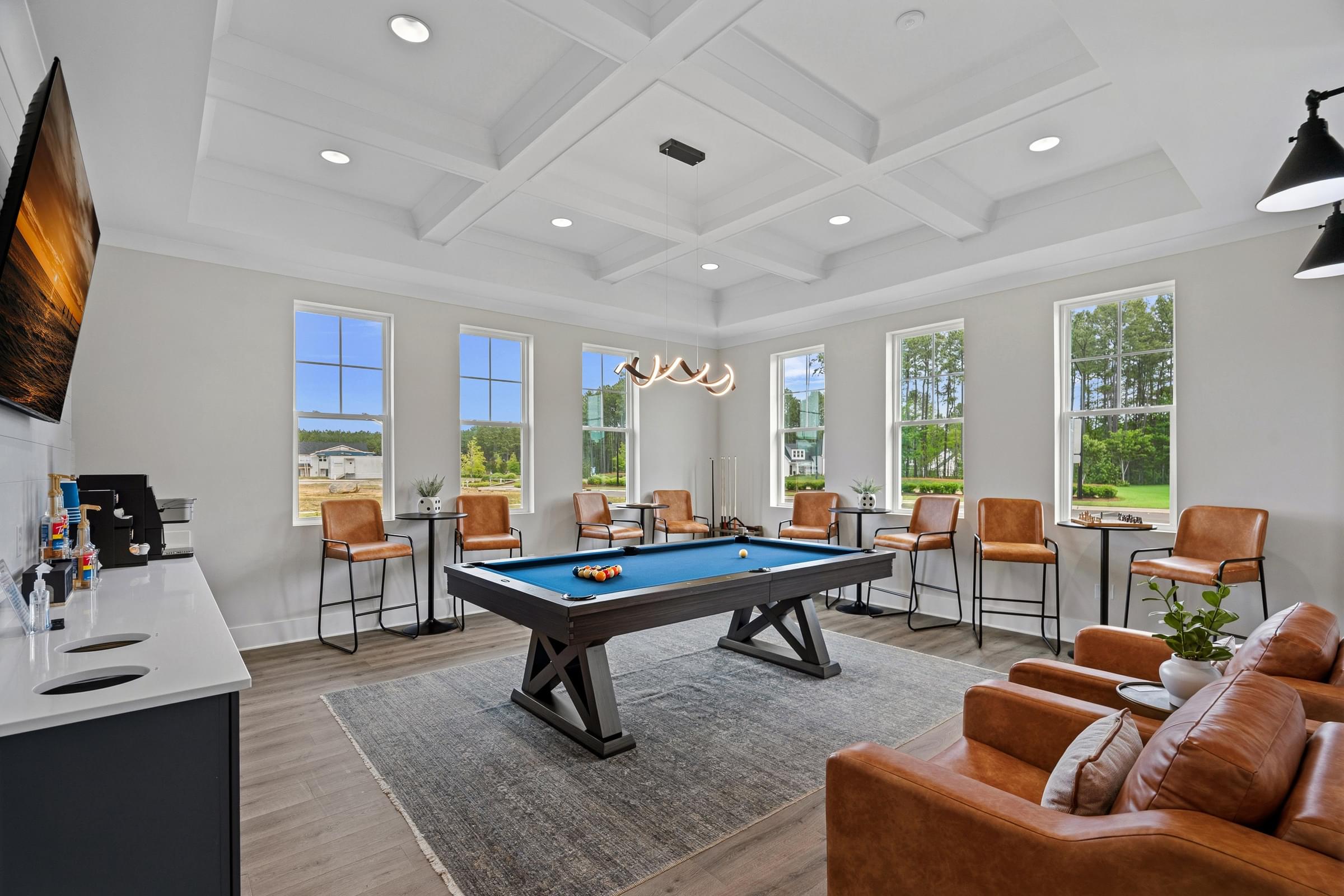 A room with a pool table and chairs.