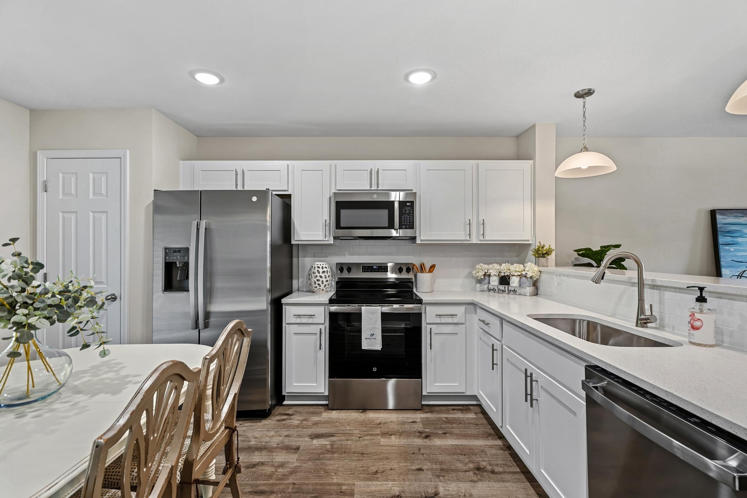 A modern kitchen with a refrigerator, oven, and sink.