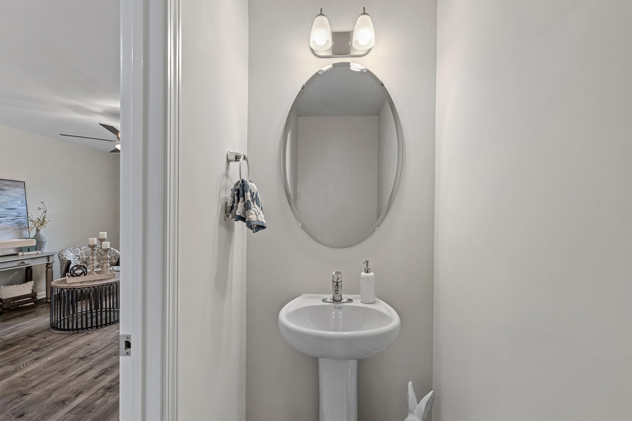 A bathroom with a white sink and a round mirror.