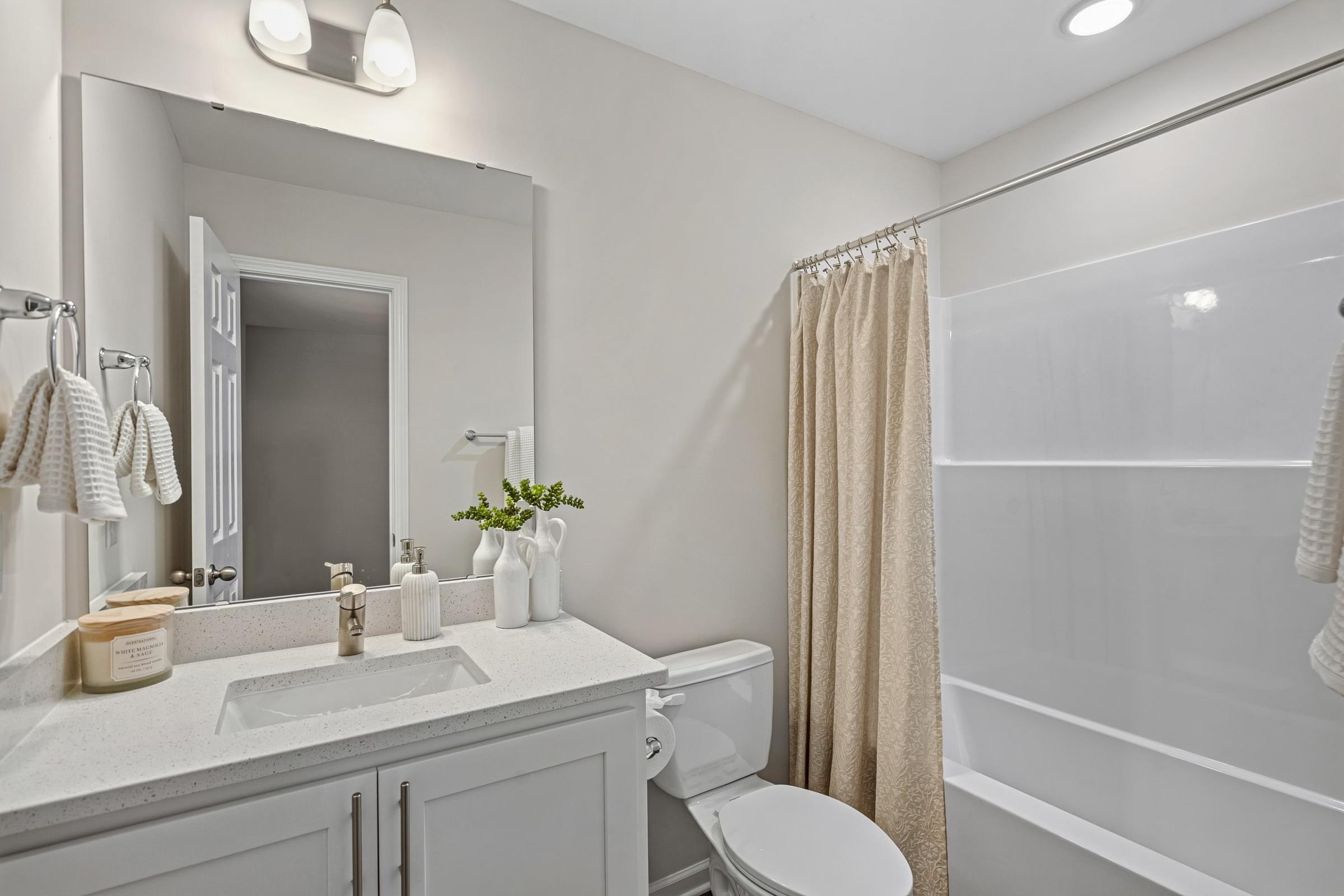 A bathroom with a white toilet, sink, and shower.
