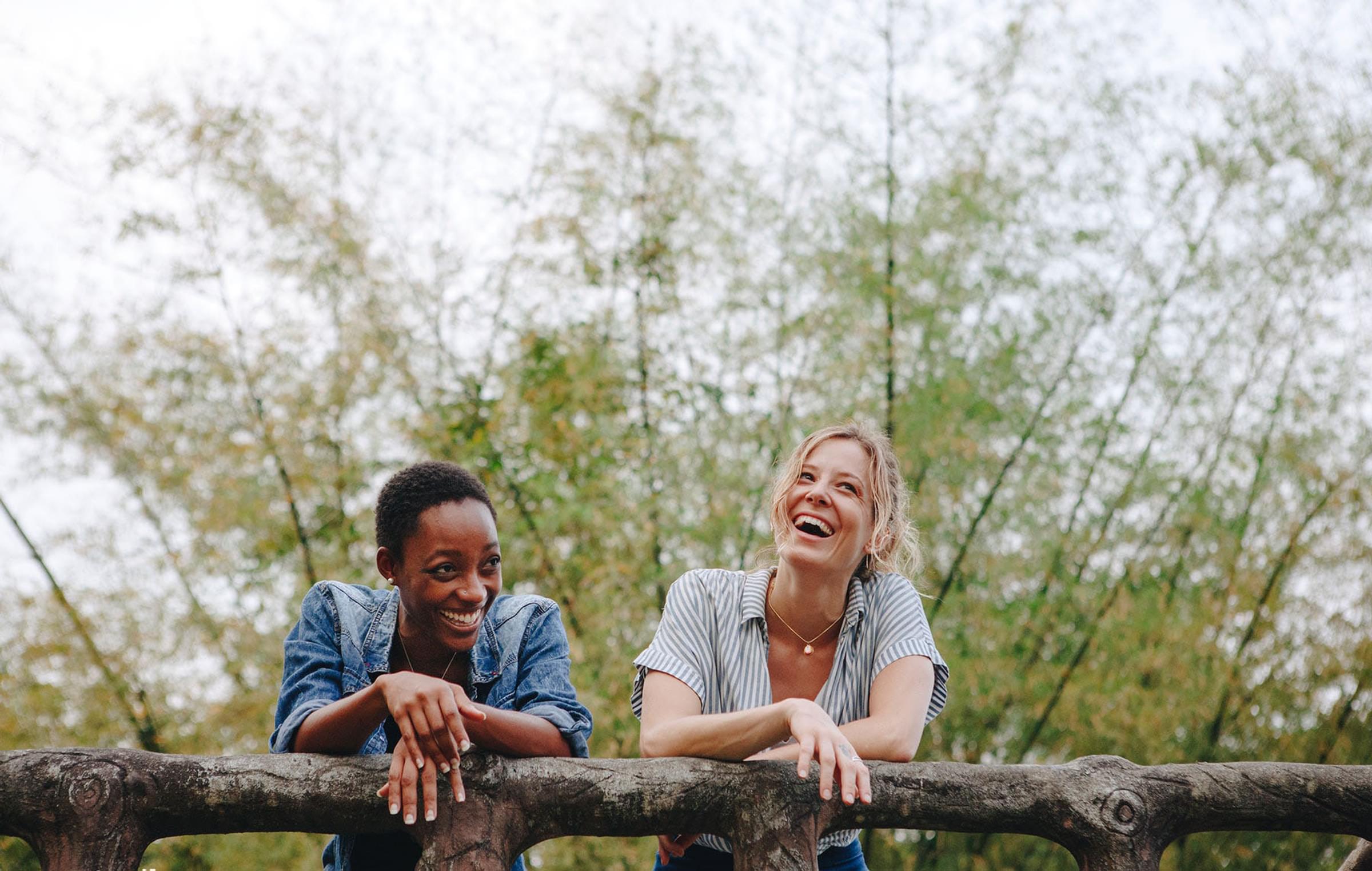 Two people leaning on a wooden fence.
