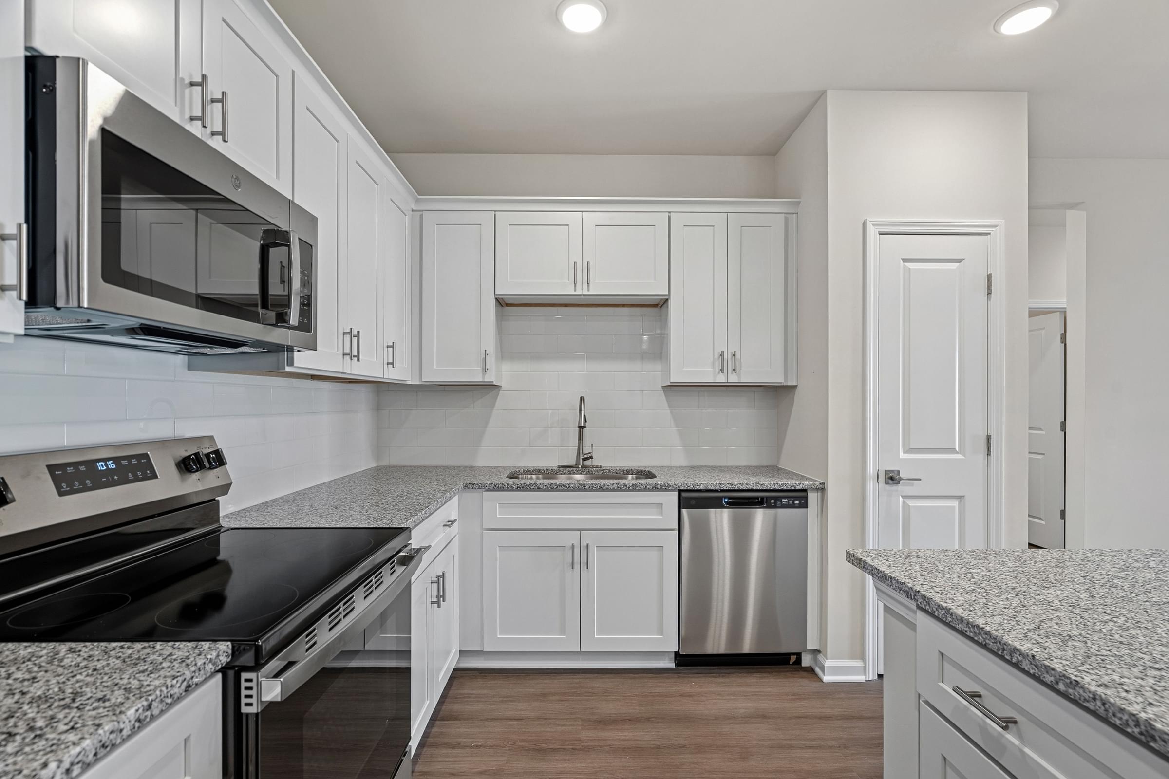 A kitchen with white cabinets and a granite countertop.