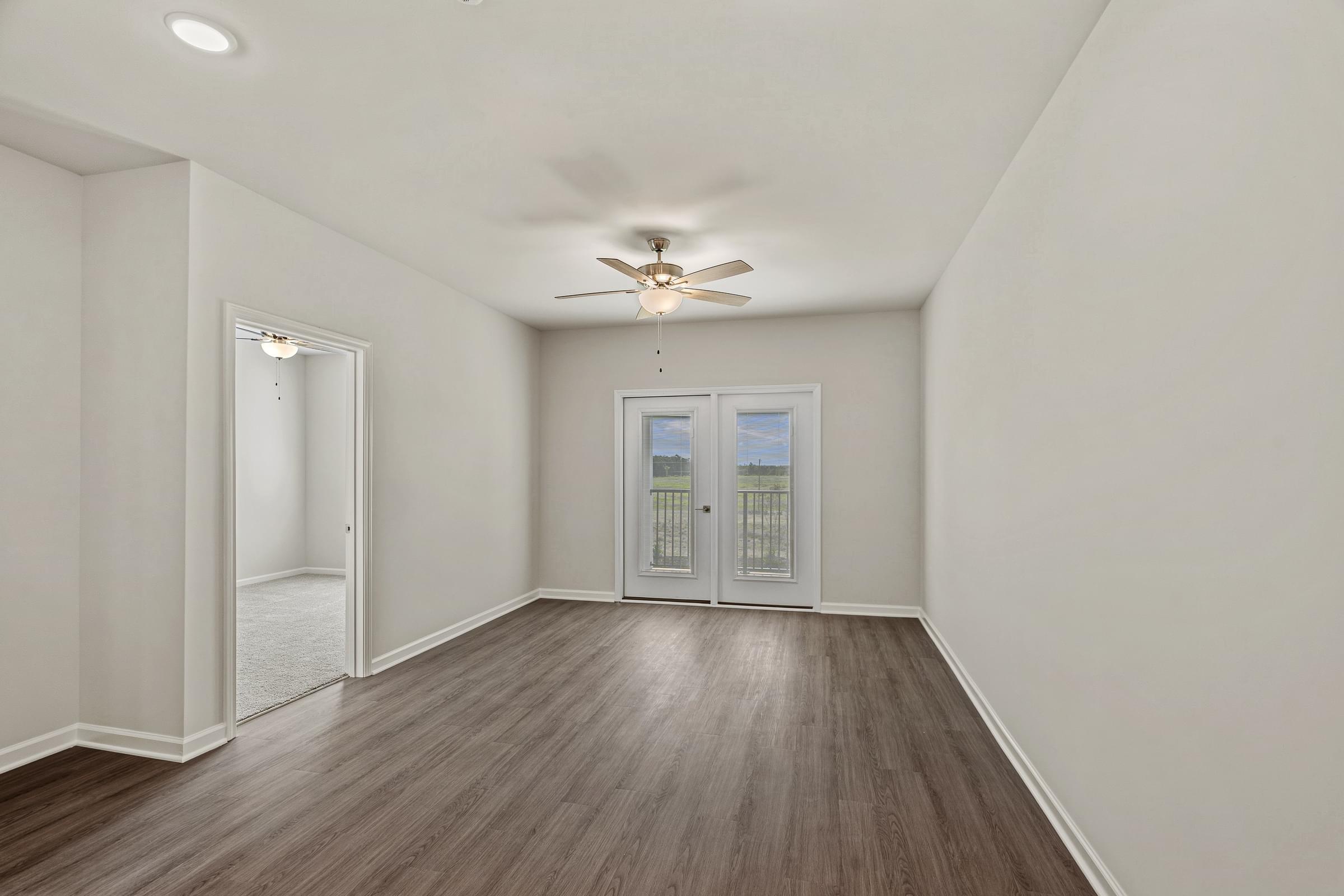 A room with a ceiling fan and a view of a building outside the window.