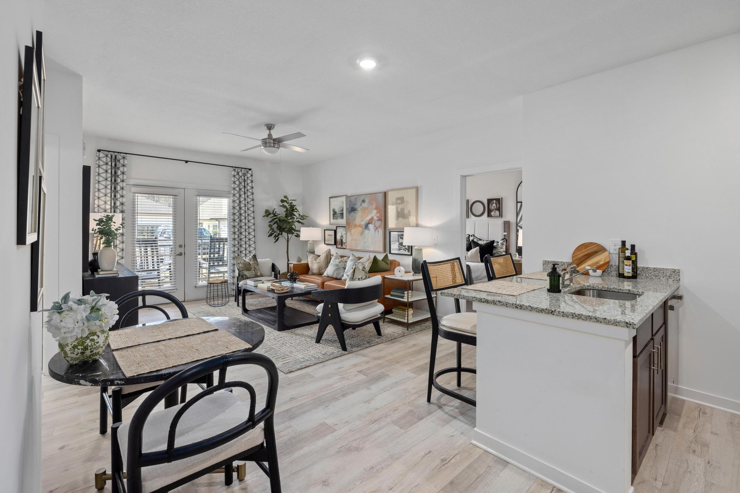 A well-lit kitchen and living room with a dining table and chairs.