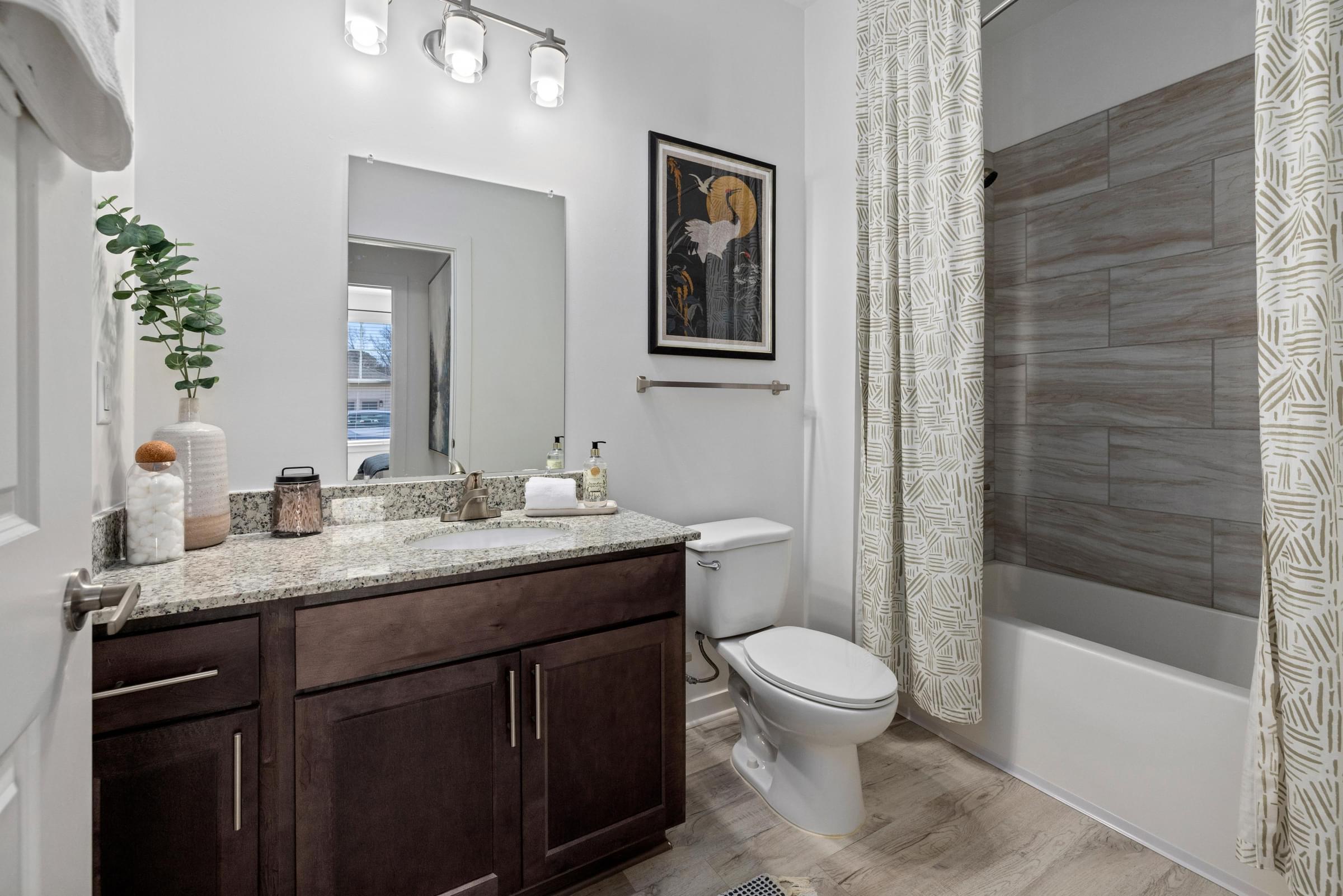 A bathroom with a toilet, sink, and a mirror.