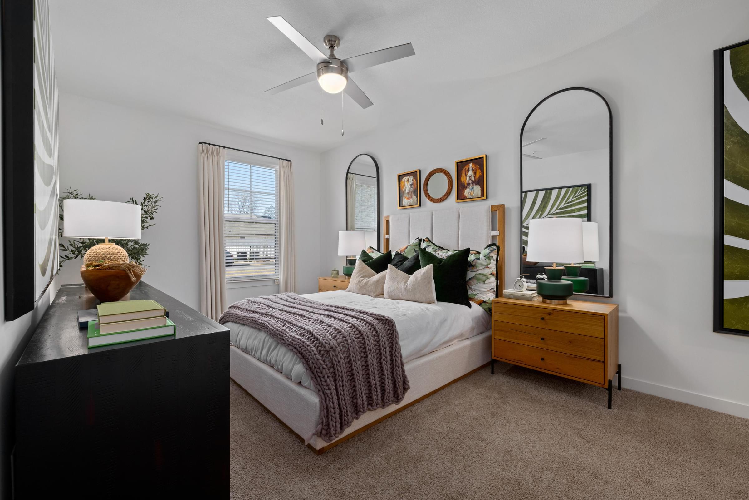 A bedroom with a bed, a dresser, and a ceiling fan.