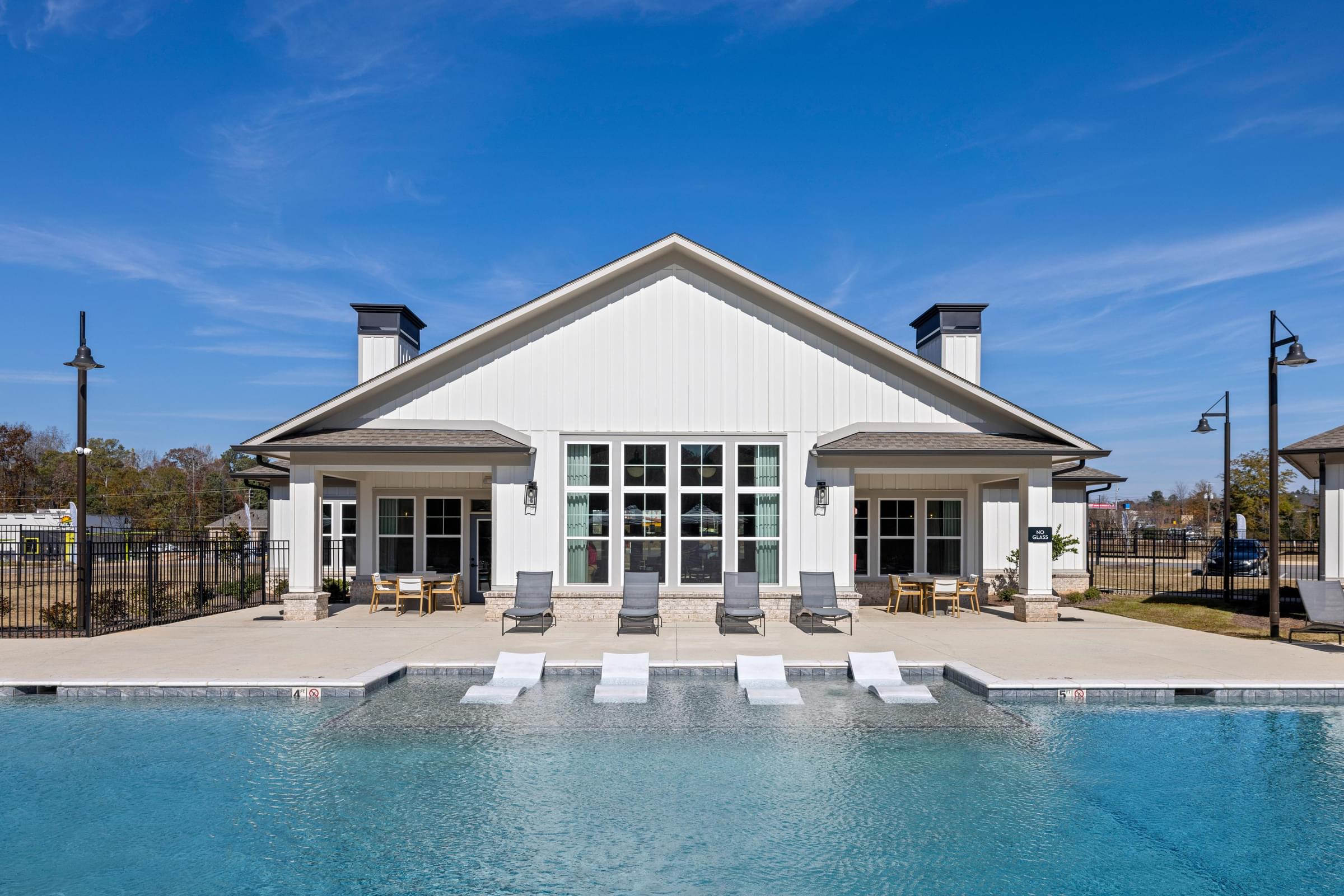 A white house with a pool in front.