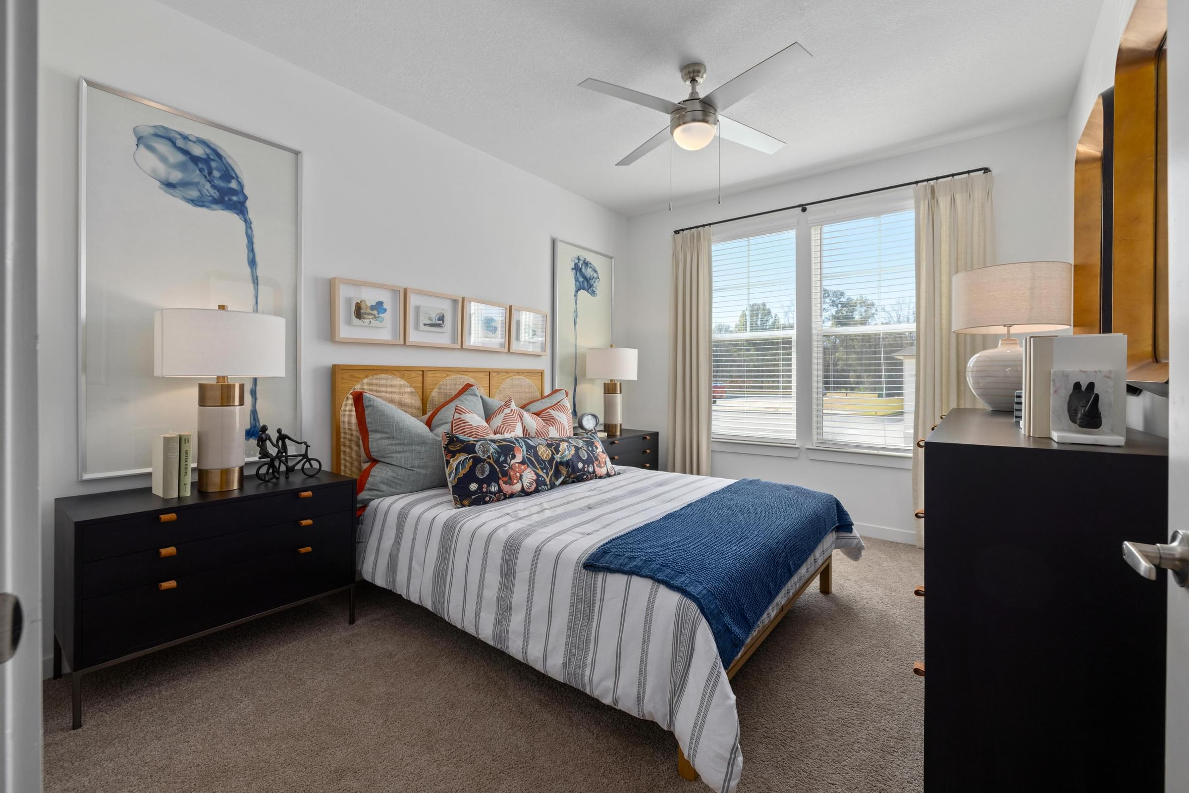 A bedroom with a bed, nightstands, and a ceiling fan.