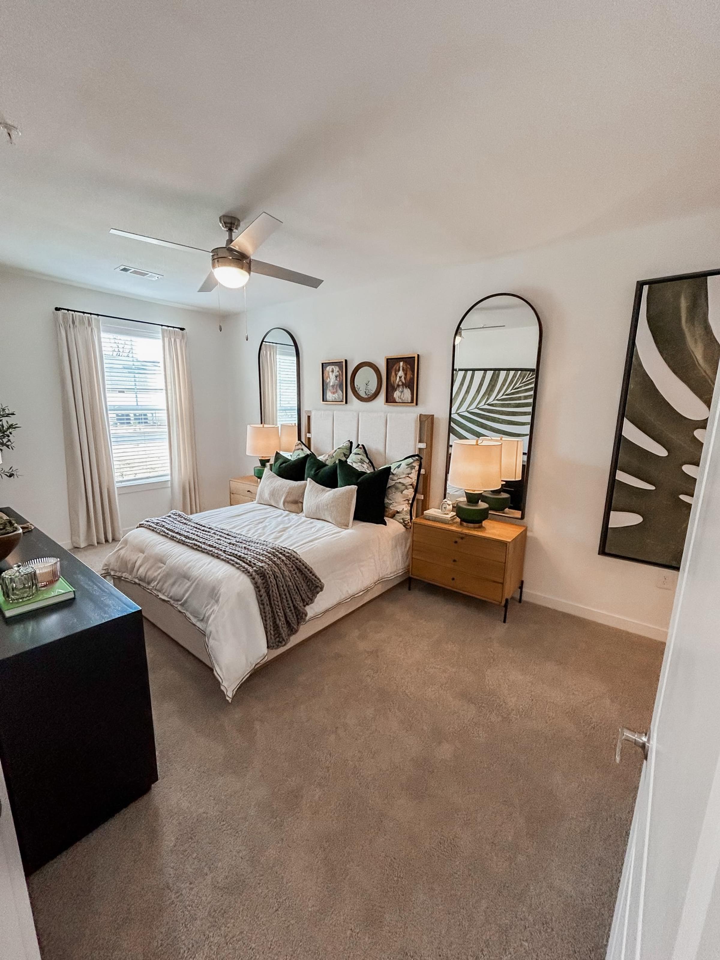A bedroom with a bed, dresser, and mirror at The Austin apartments in Opelika, AL.