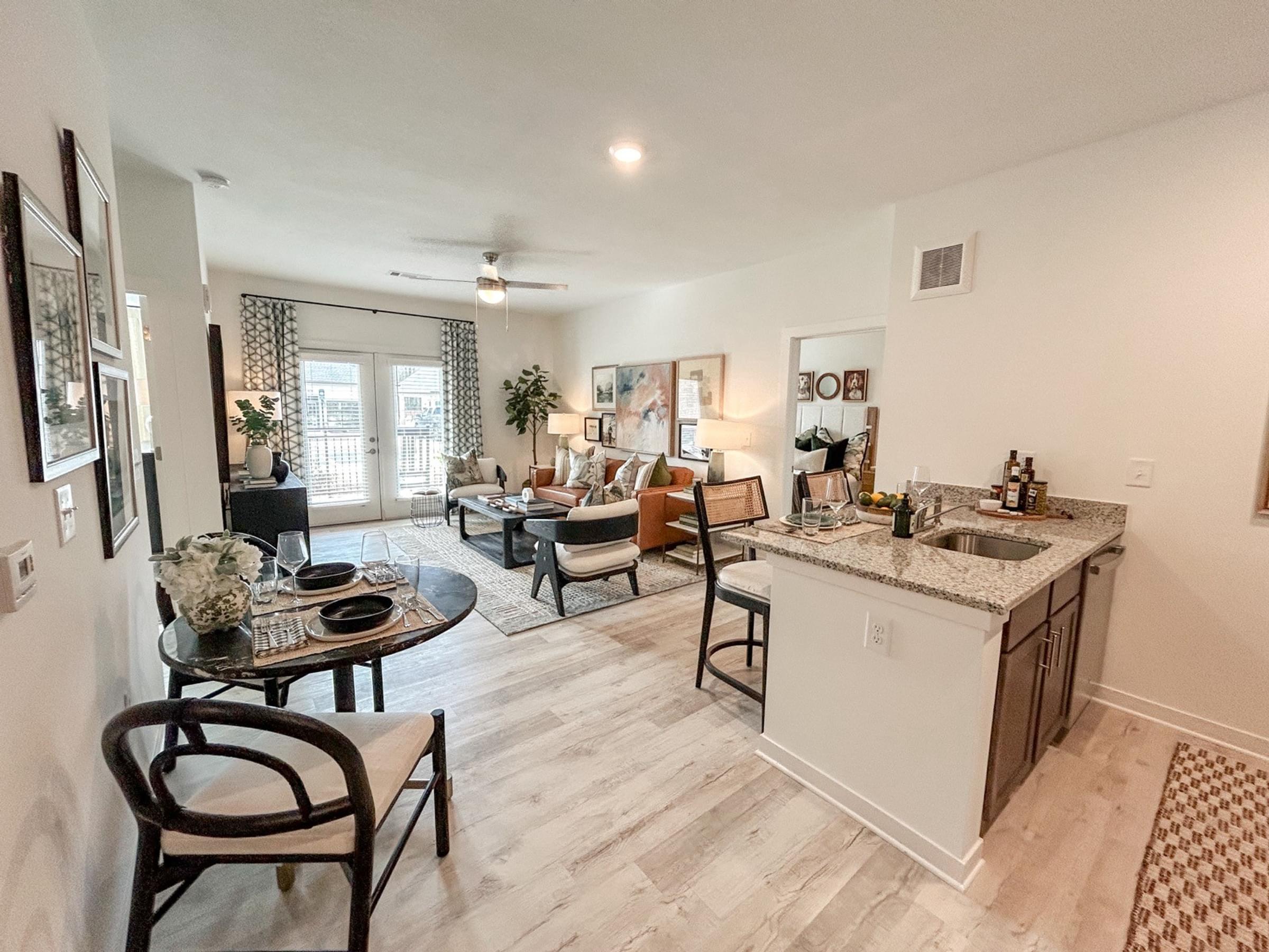 A kitchen and living room with a dining table and chairs at The Austin apartments in Opelika, AL.