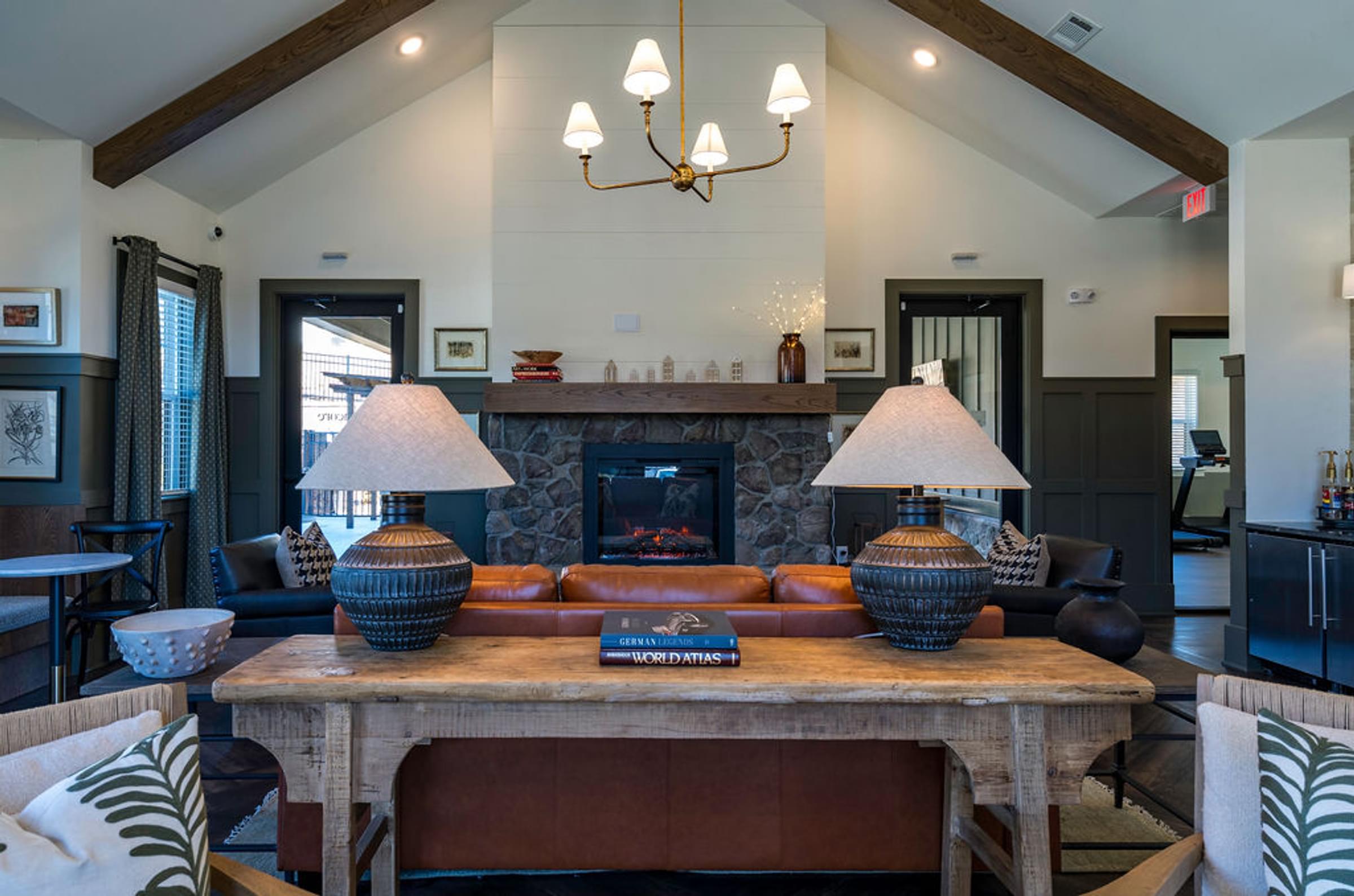 A living room with a fireplace and a table with two lamps on it.