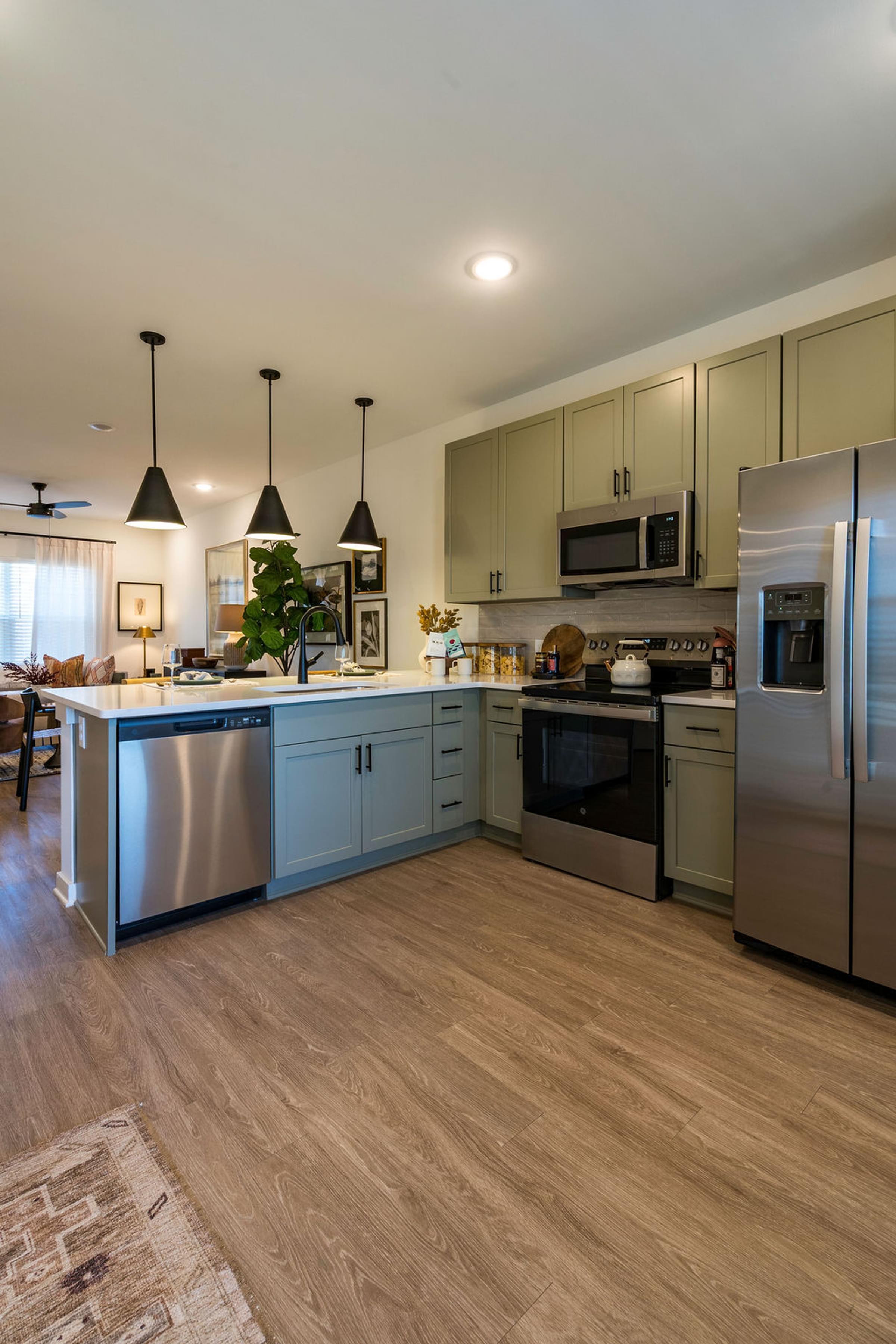 A kitchen with a stainless steel refrigerator and wooden flooring.