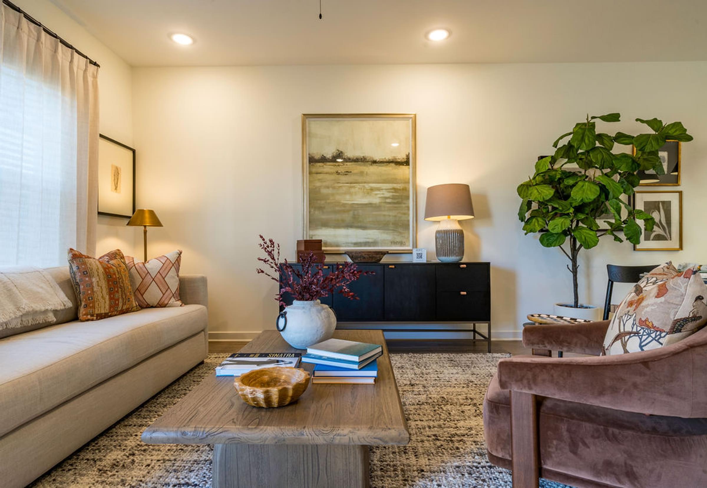 A living room with a sofa, a chair, a coffee table, and a painting on the wall.