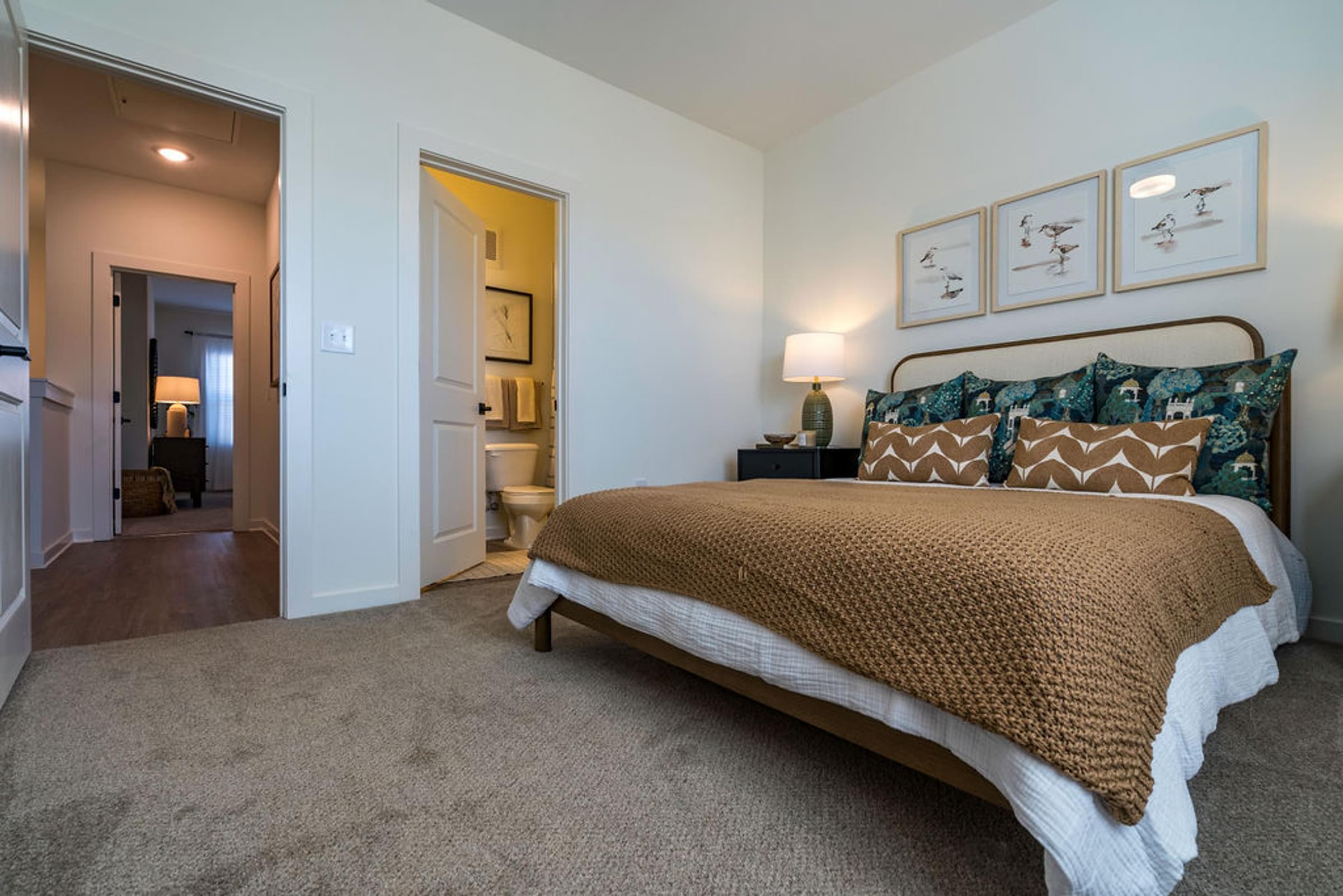 A bedroom with a bed, a lamp, and pictures on the wall.