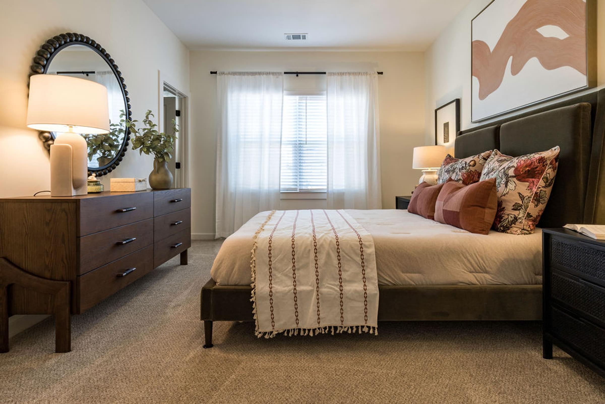 A bedroom with a bed, nightstand, and a dresser.