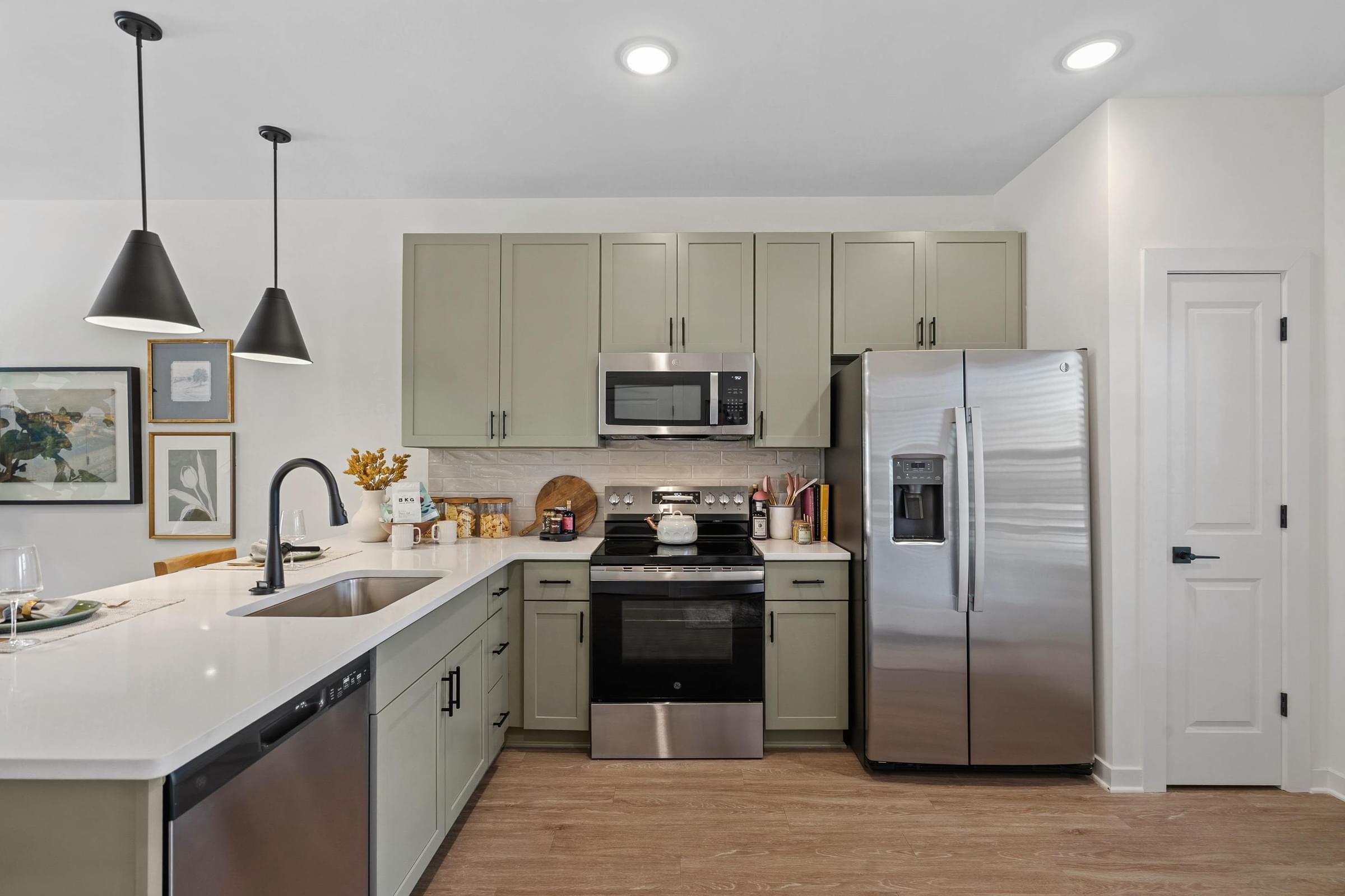 A kitchen with a refrigerator, sink, and cabinets.