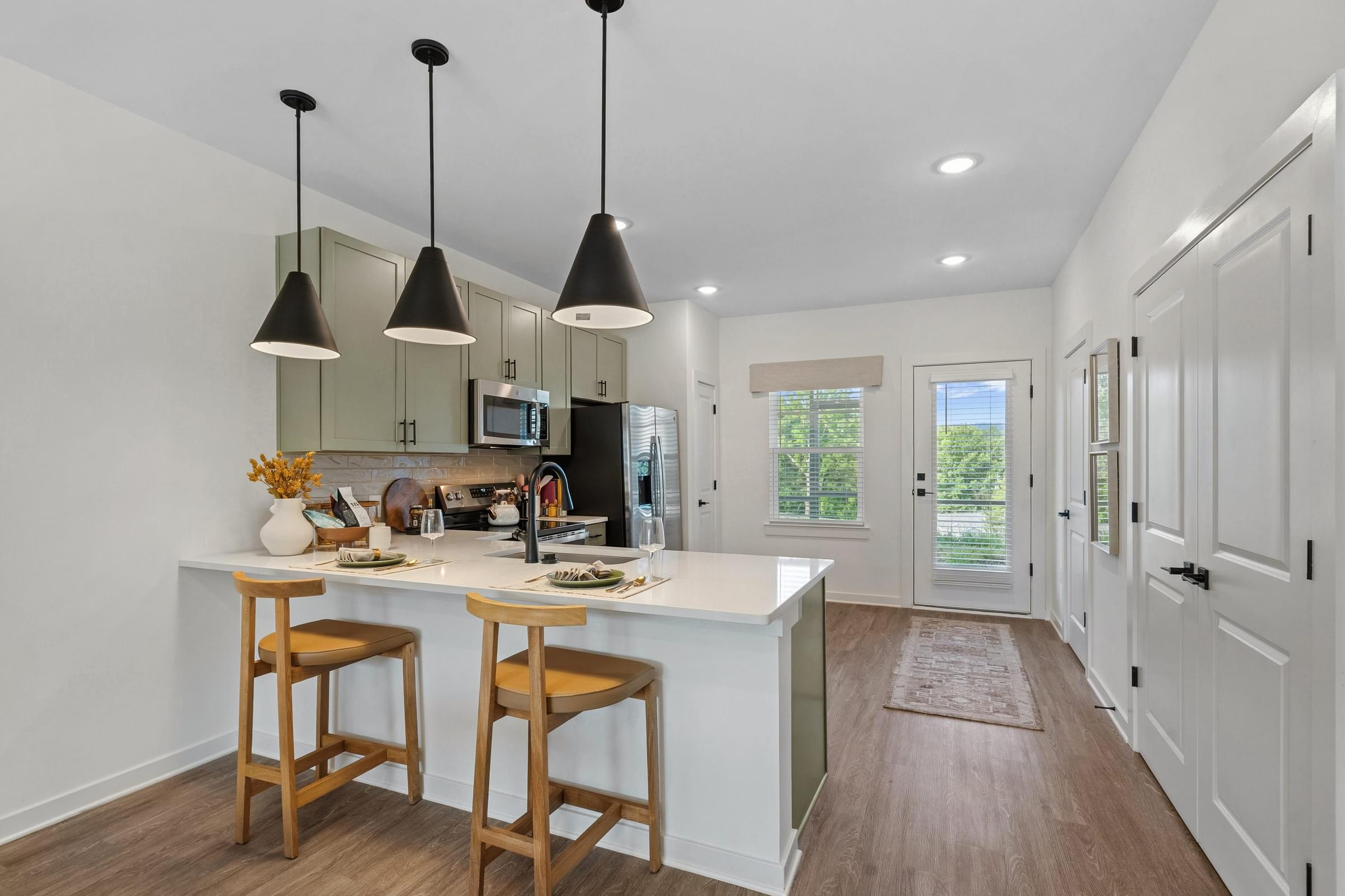 A kitchen with a white counter and wooden bar stools.
