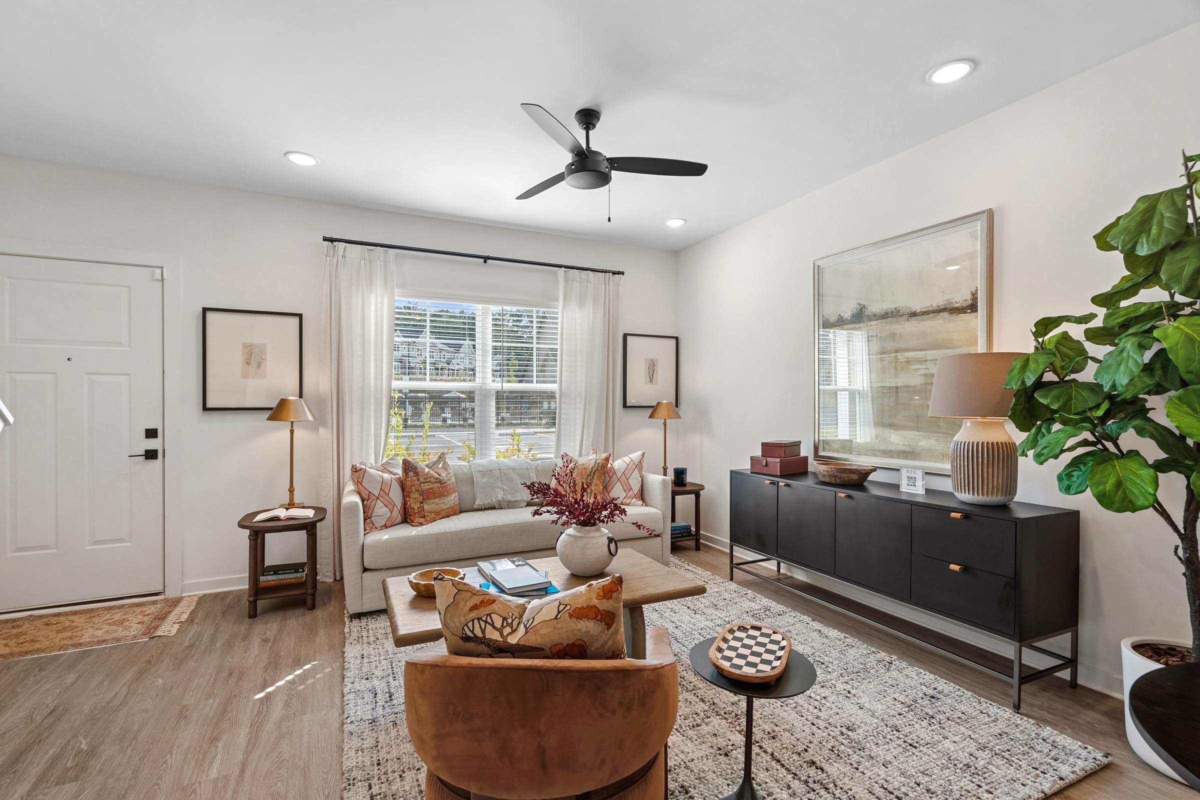 A living room with a brown chair and a white ceiling fan.