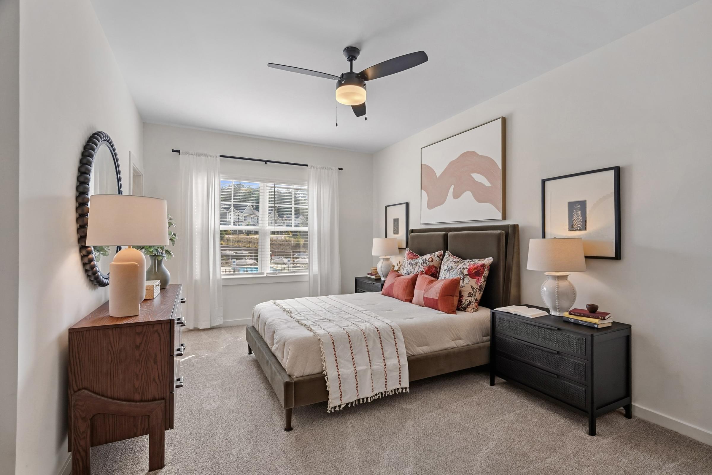 A bedroom with a bed, nightstand, and a ceiling fan.
