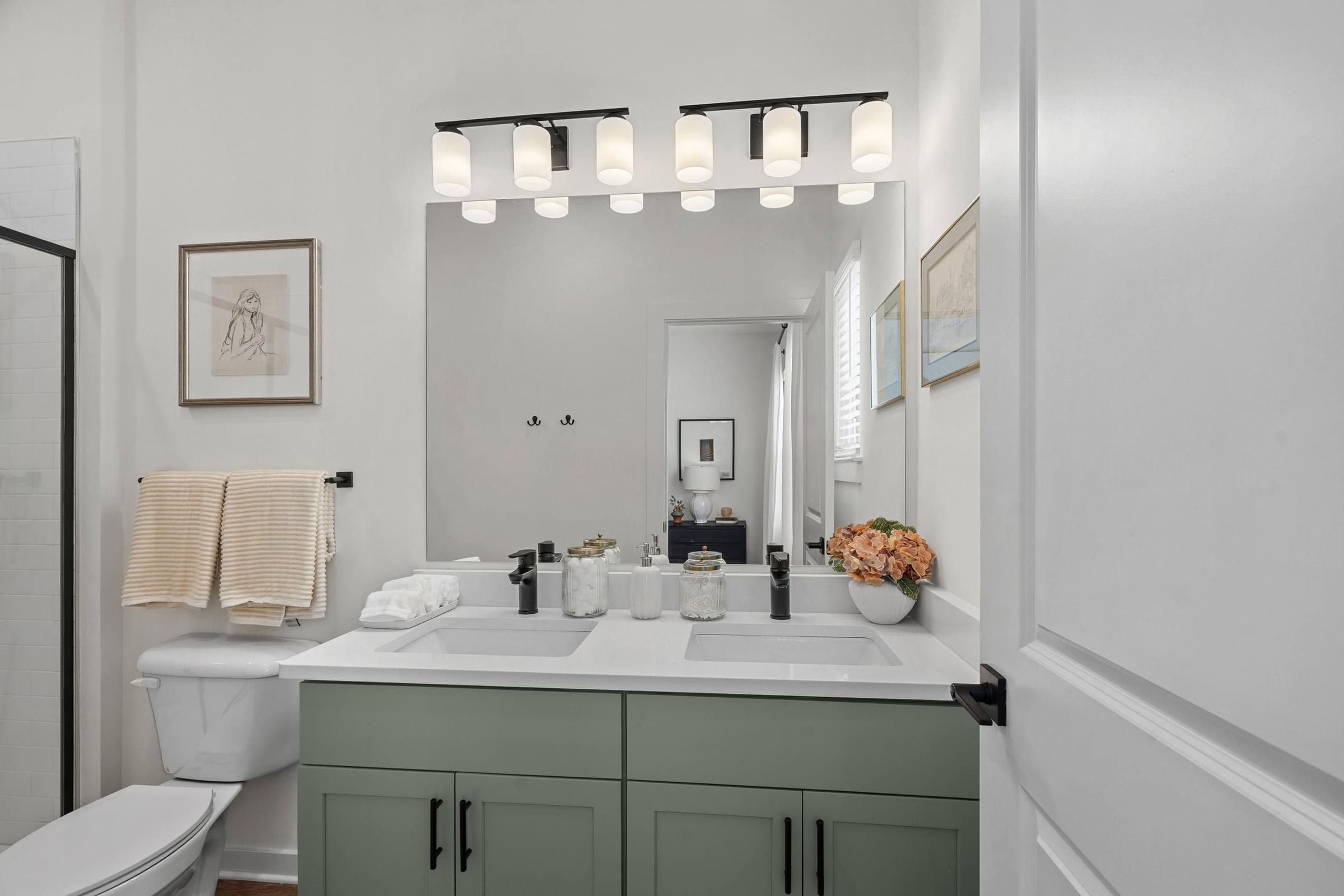 A bathroom with a white toilet, a sink with a mirror above it, and a towel hanging on the wall.