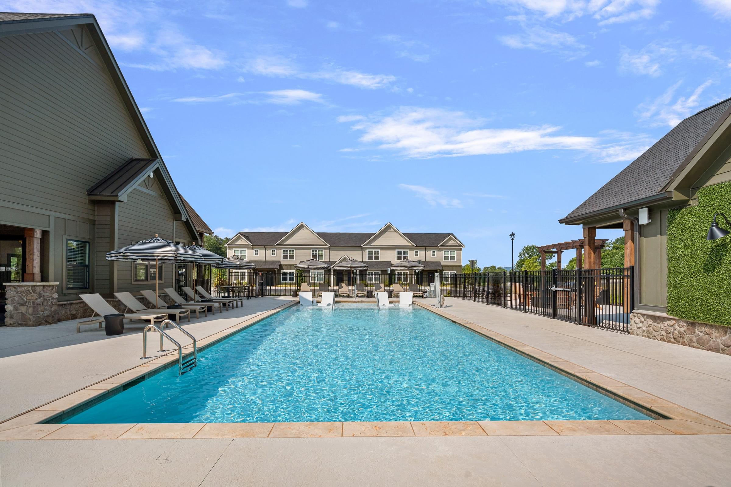 A large swimming pool surrounded by a black fence and a building in the background.