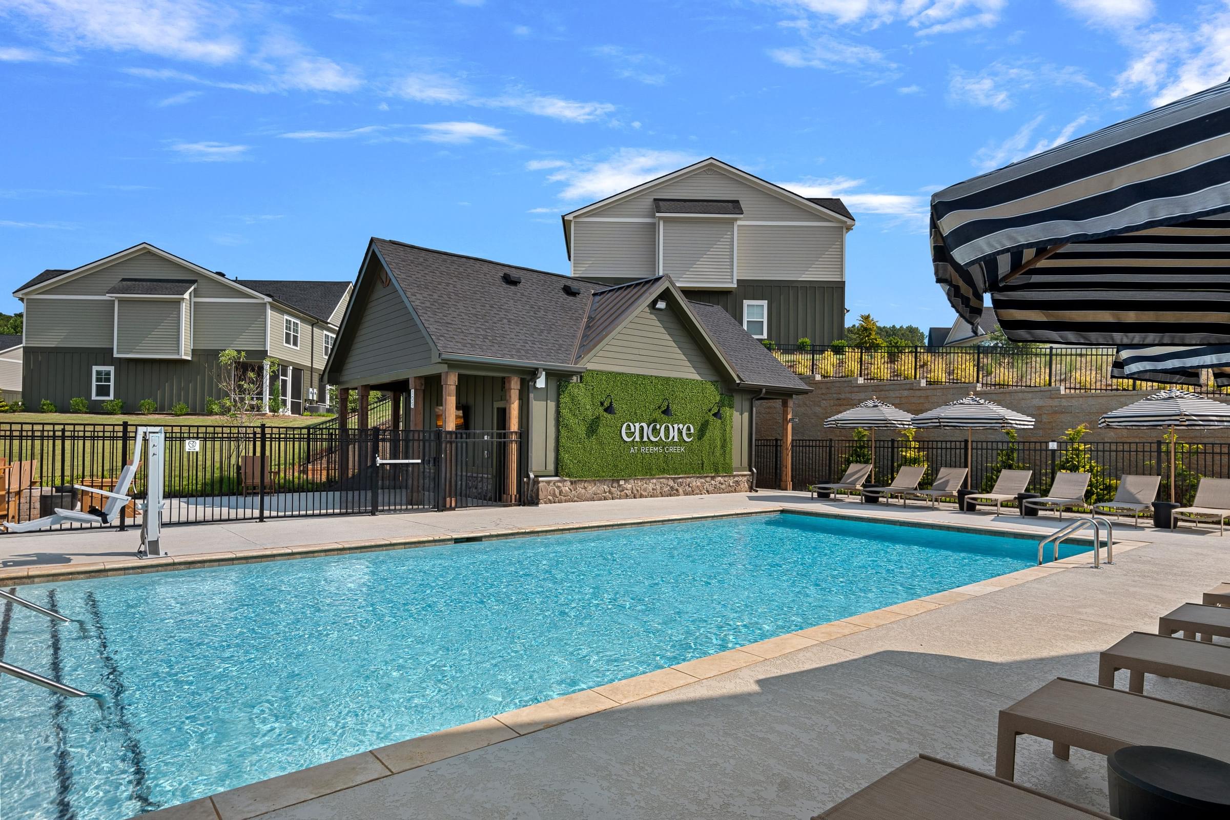 A pool surrounded by lounge chairs and umbrellas with a sign that says