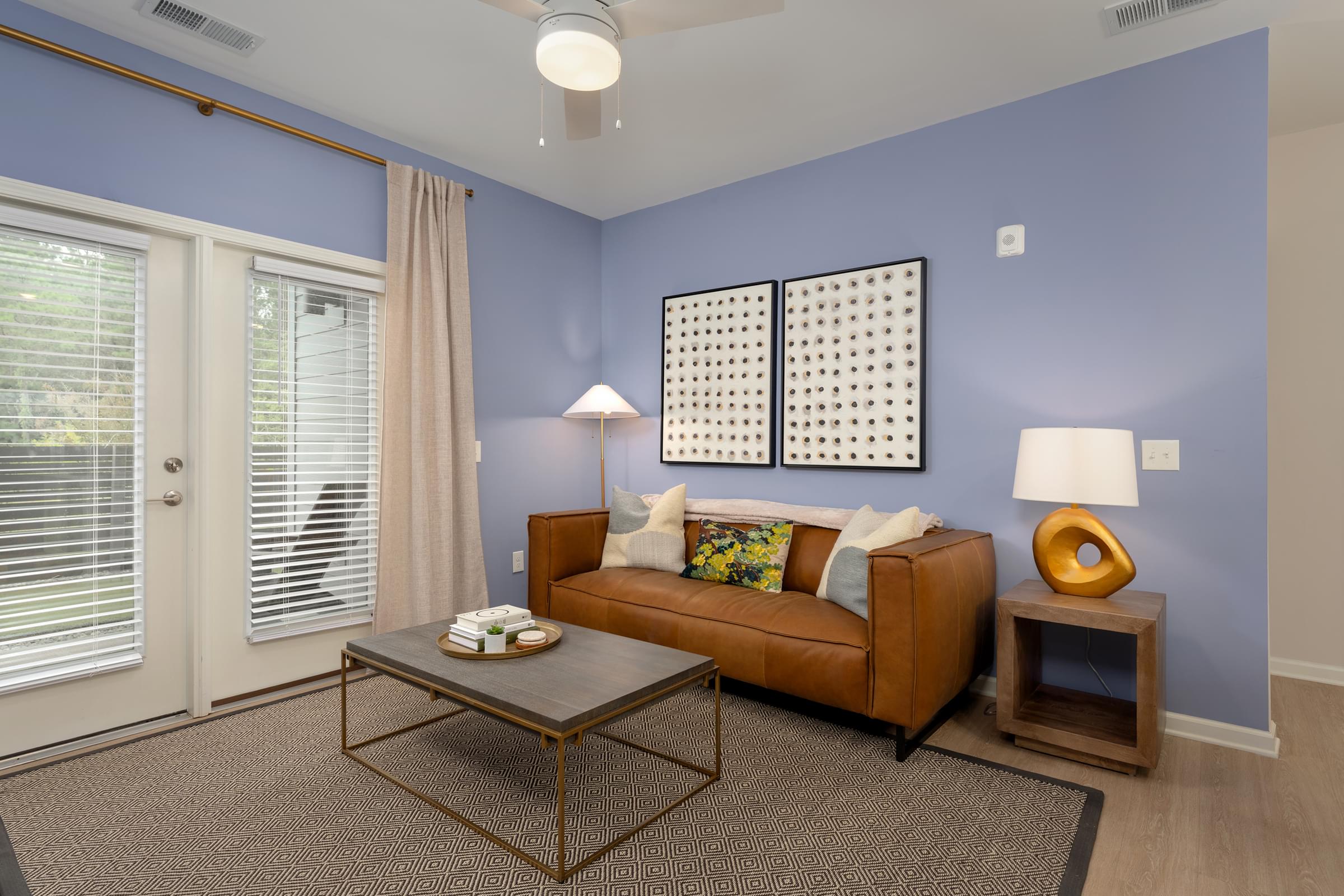 A living room with a brown couch, a coffee table, and a large painting on the wall.