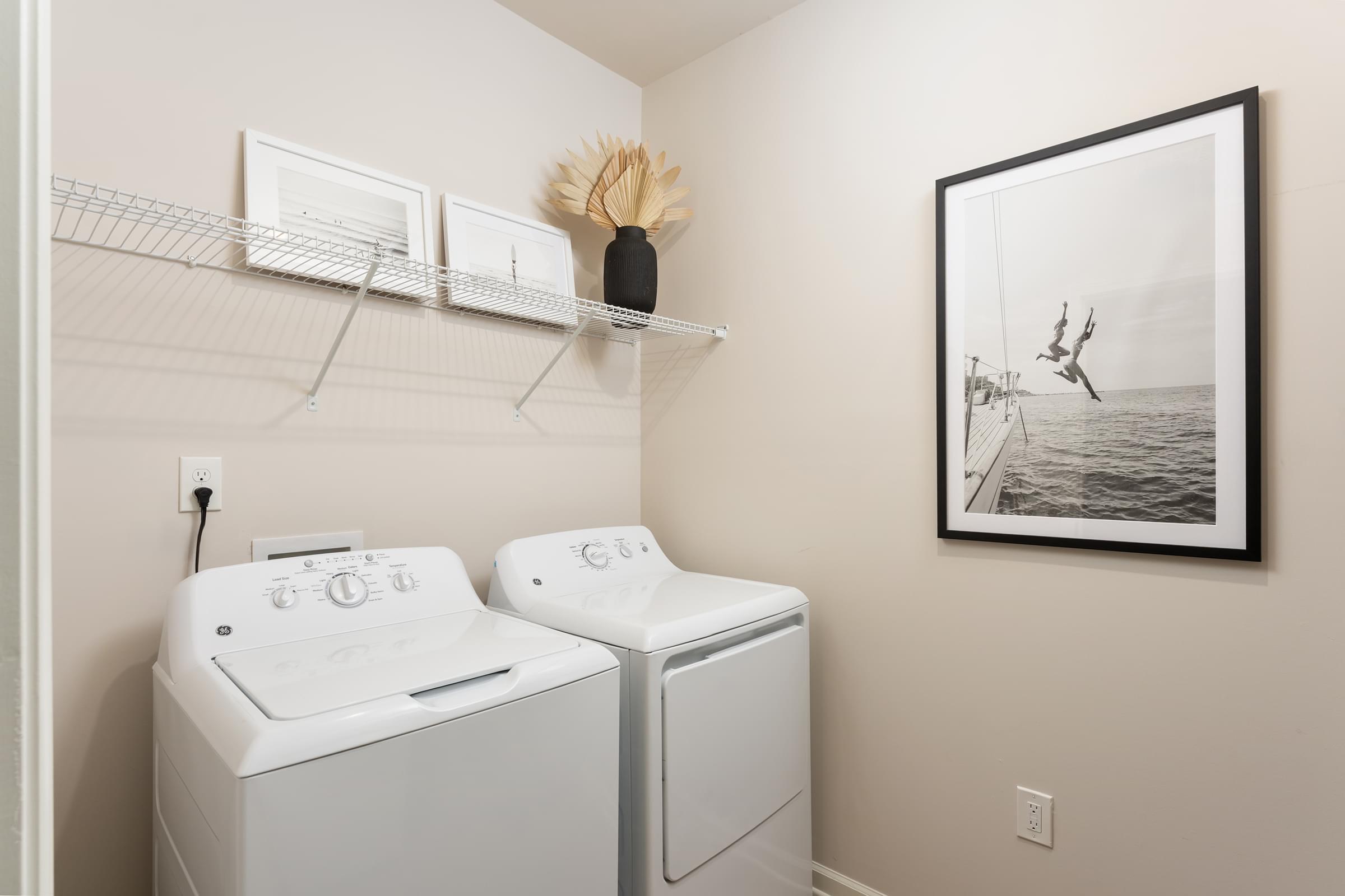 A laundry room with two washing machines and a picture of a person skydiving on the wall.