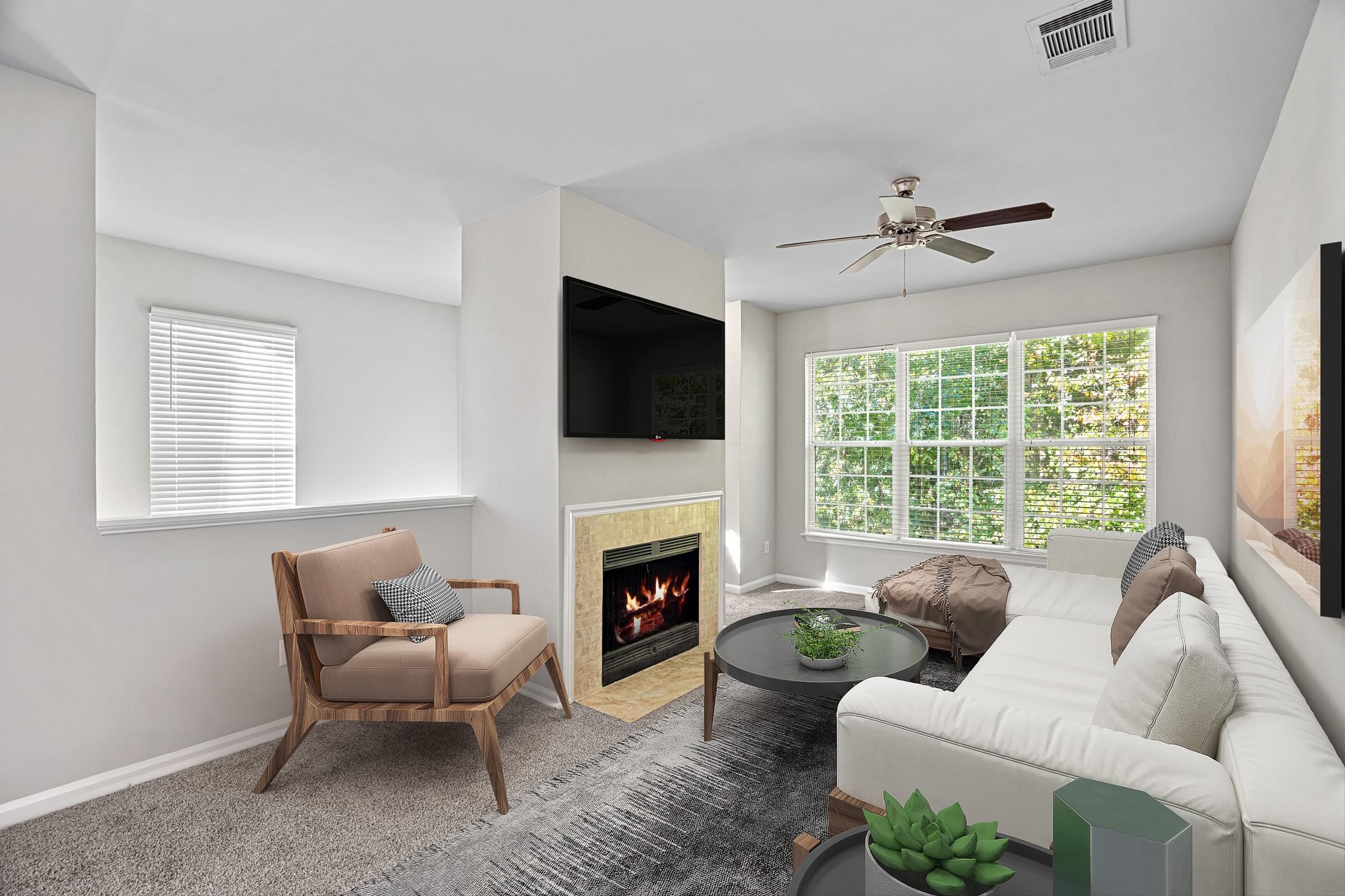 A living room with a fireplace, a chair, a couch, and a television at Hawthorne Bridford in Greensboro, NC.