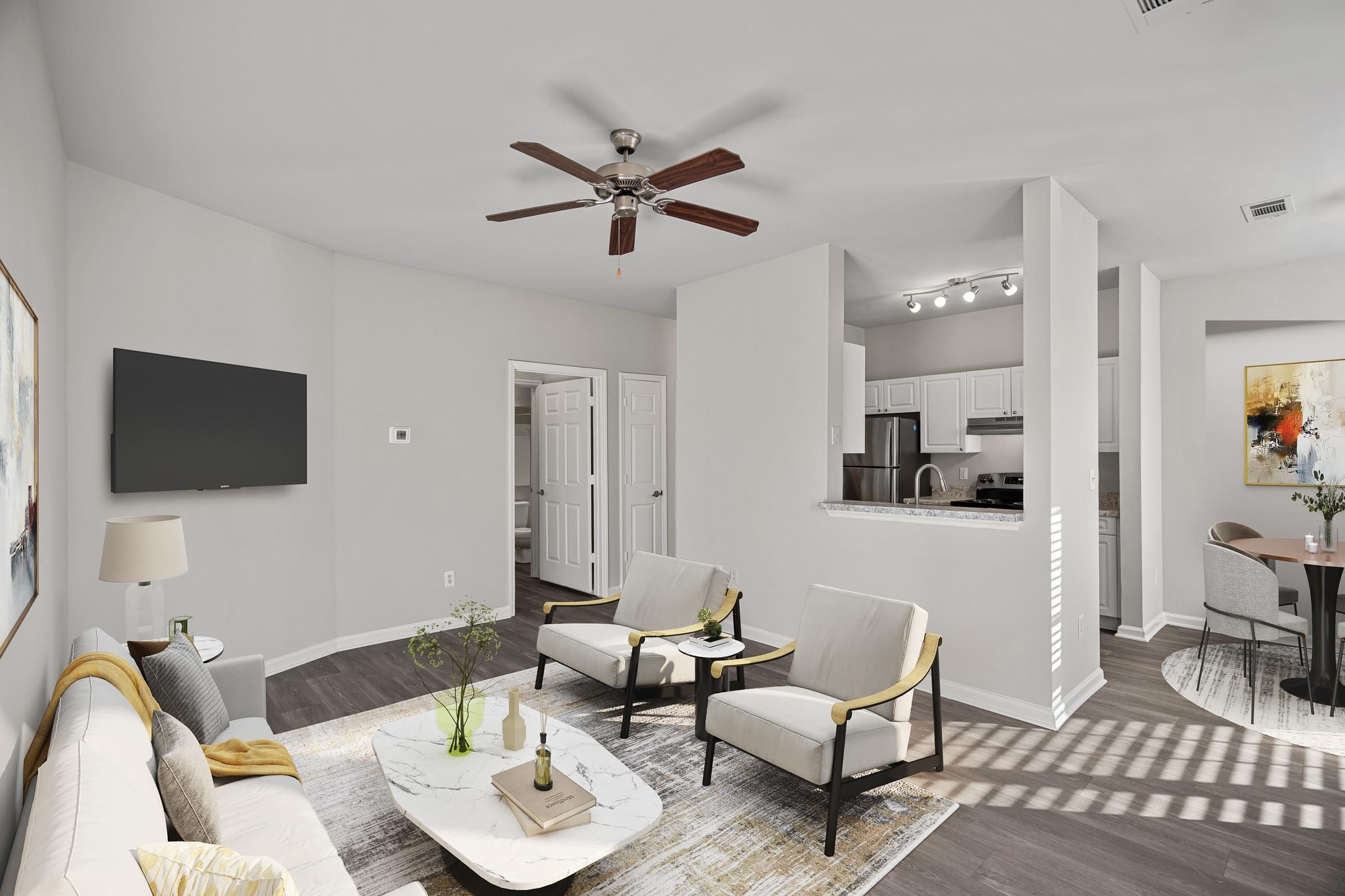 A living room with a white couch, a coffee table, and a ceiling fan at Hawthorne Bridford in Greensboro, NC