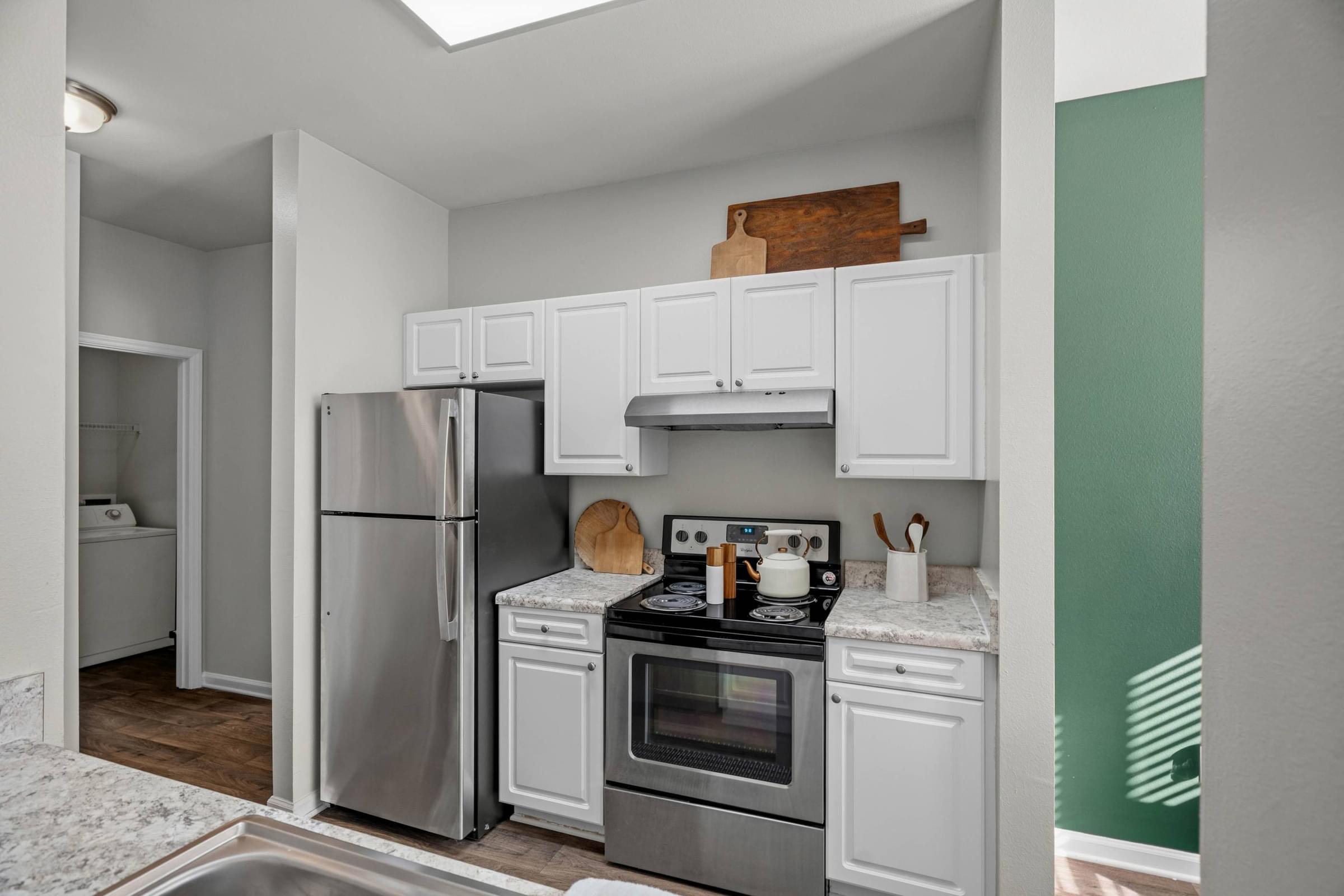A kitchen with white cabinets and a stainless steel refrigerator.