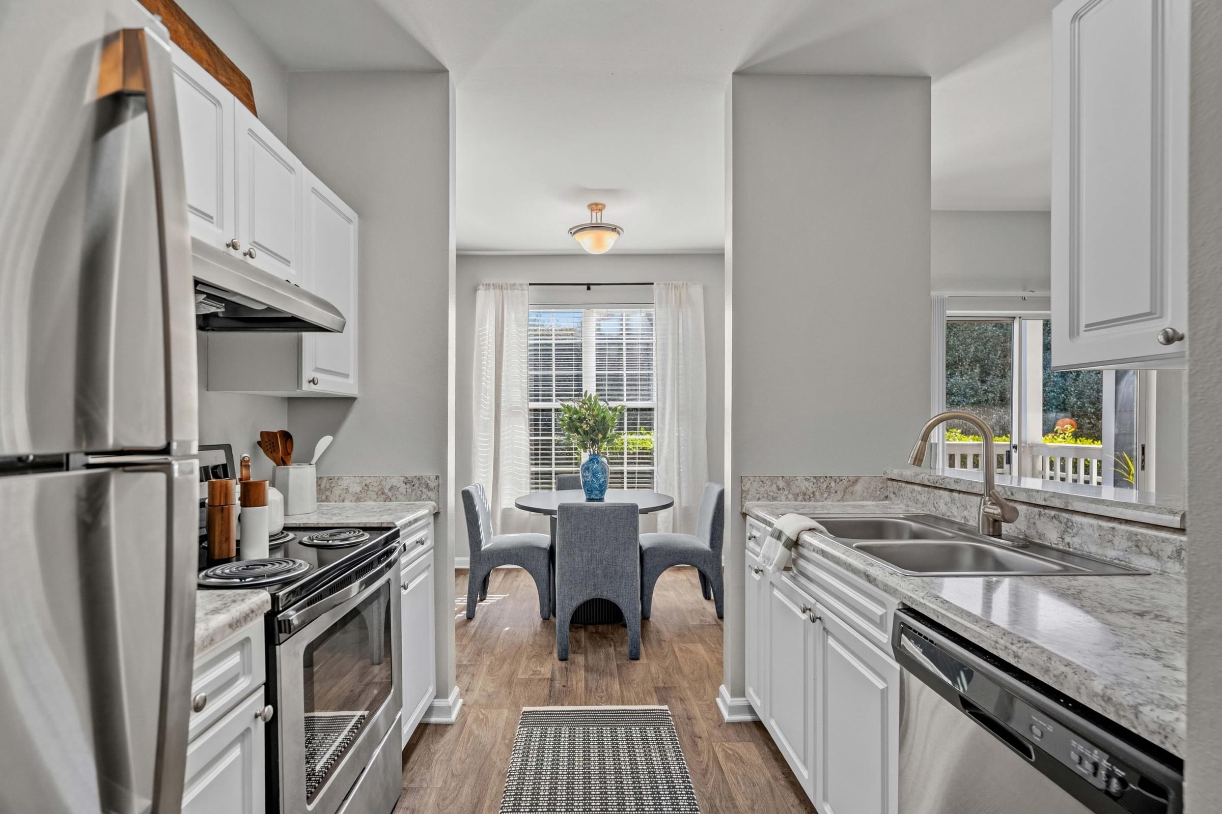 A kitchen with a refrigerator, oven, and sink.