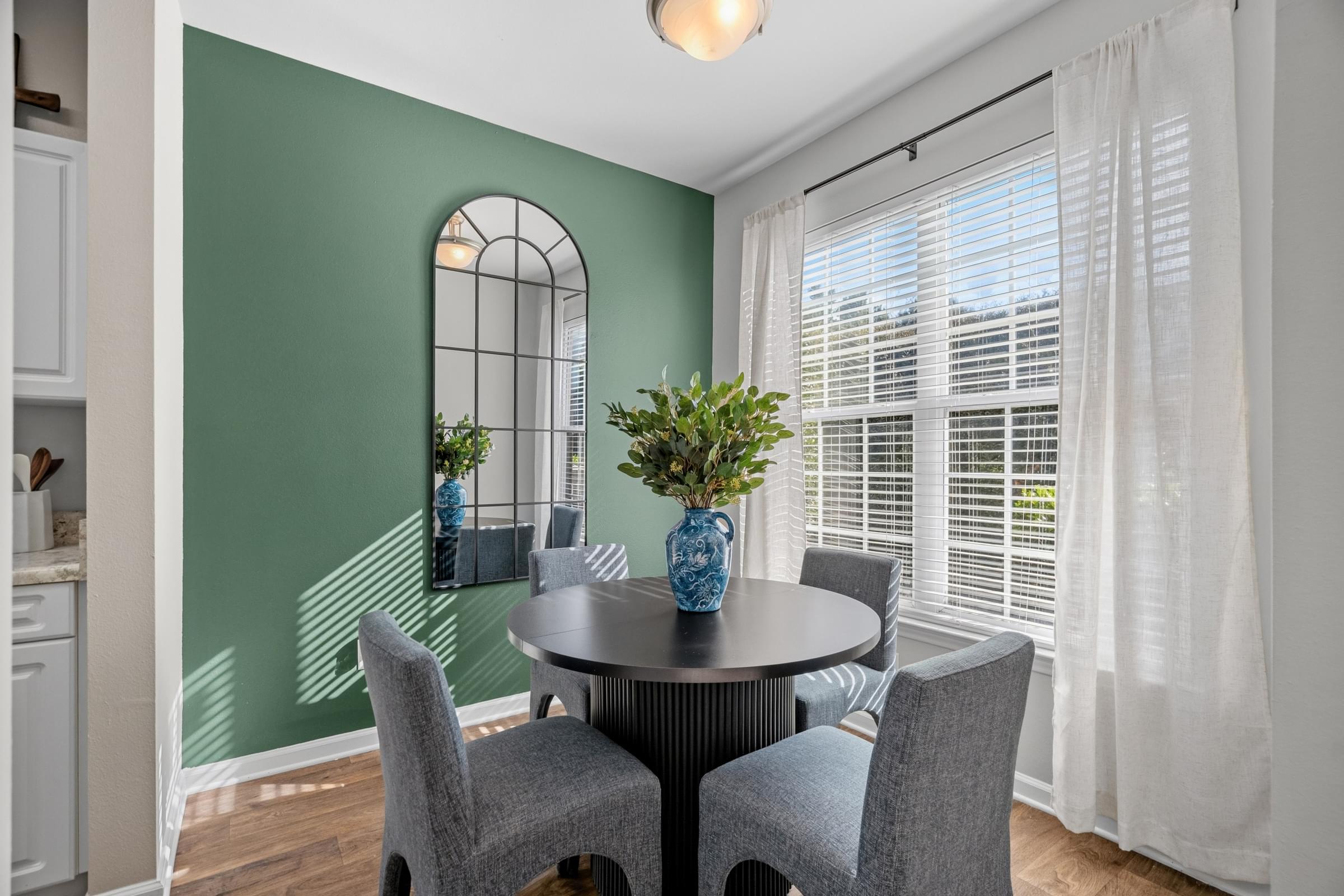 A dining room with a round table and grey chairs.