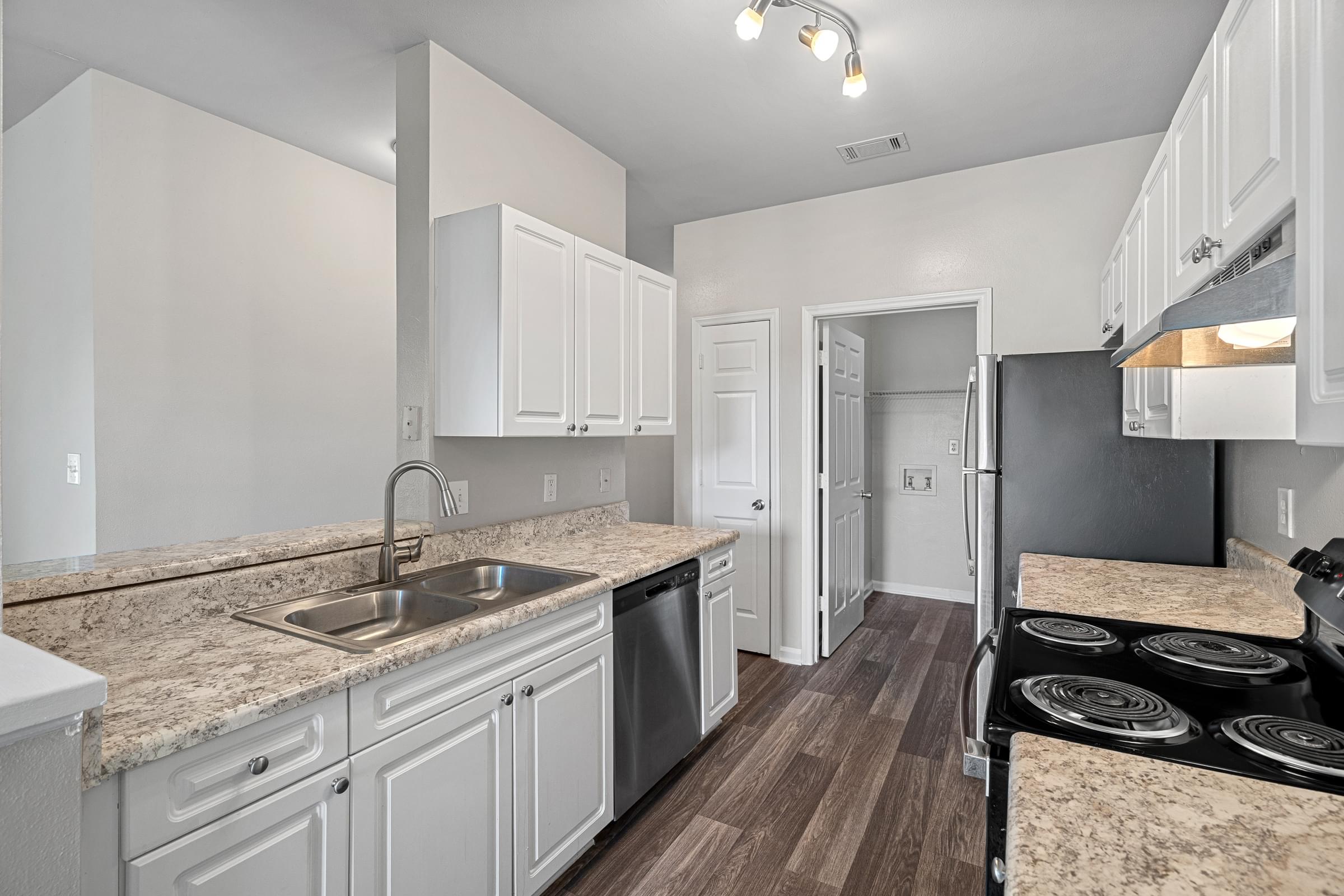 A kitchen with white cabinets and a granite countertop.