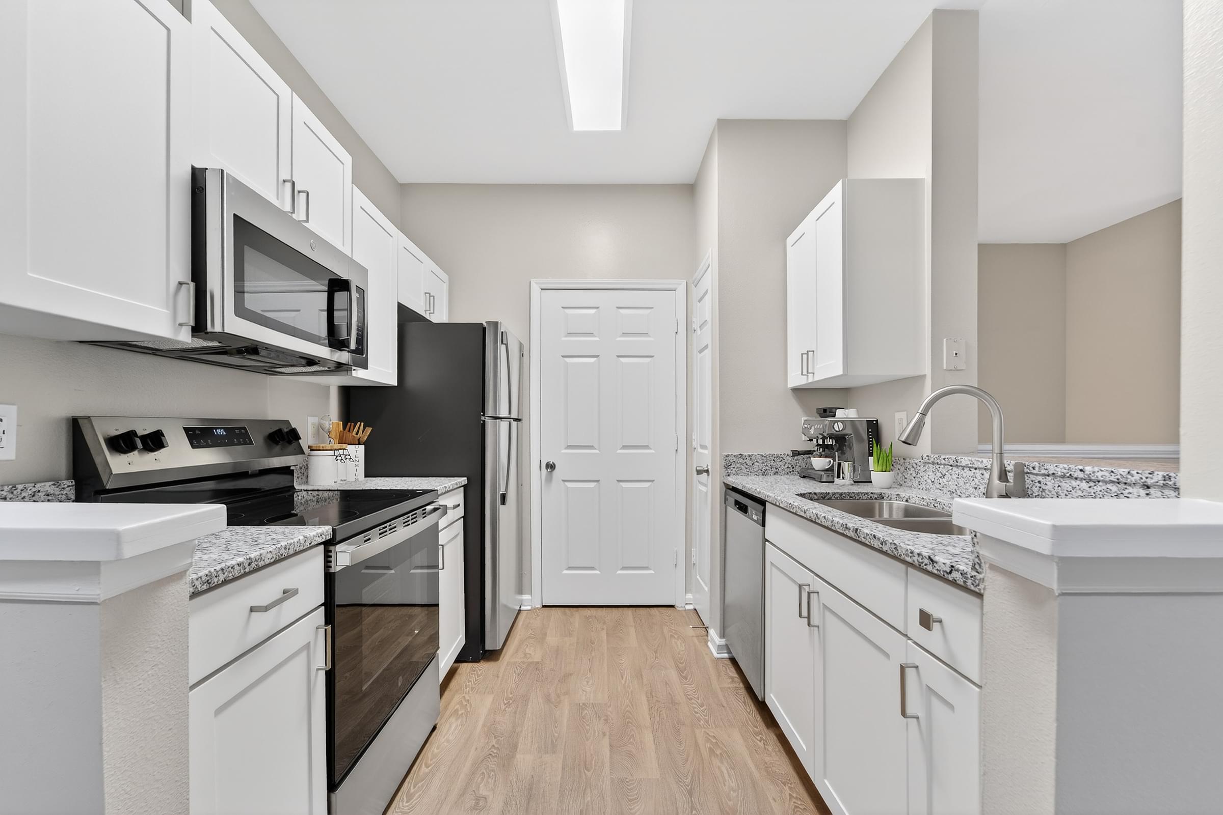 A kitchen with white cabinets and a black refrigerator.